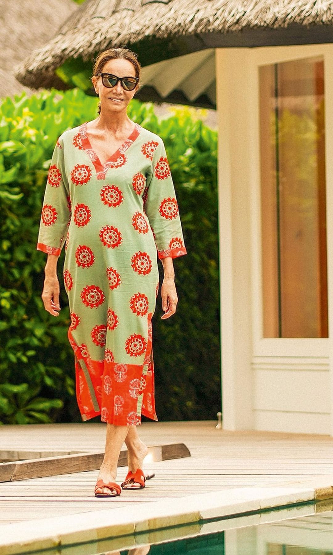  Isabel con un vestido estilo caftán, en verde y rojo, al lado de la piscina