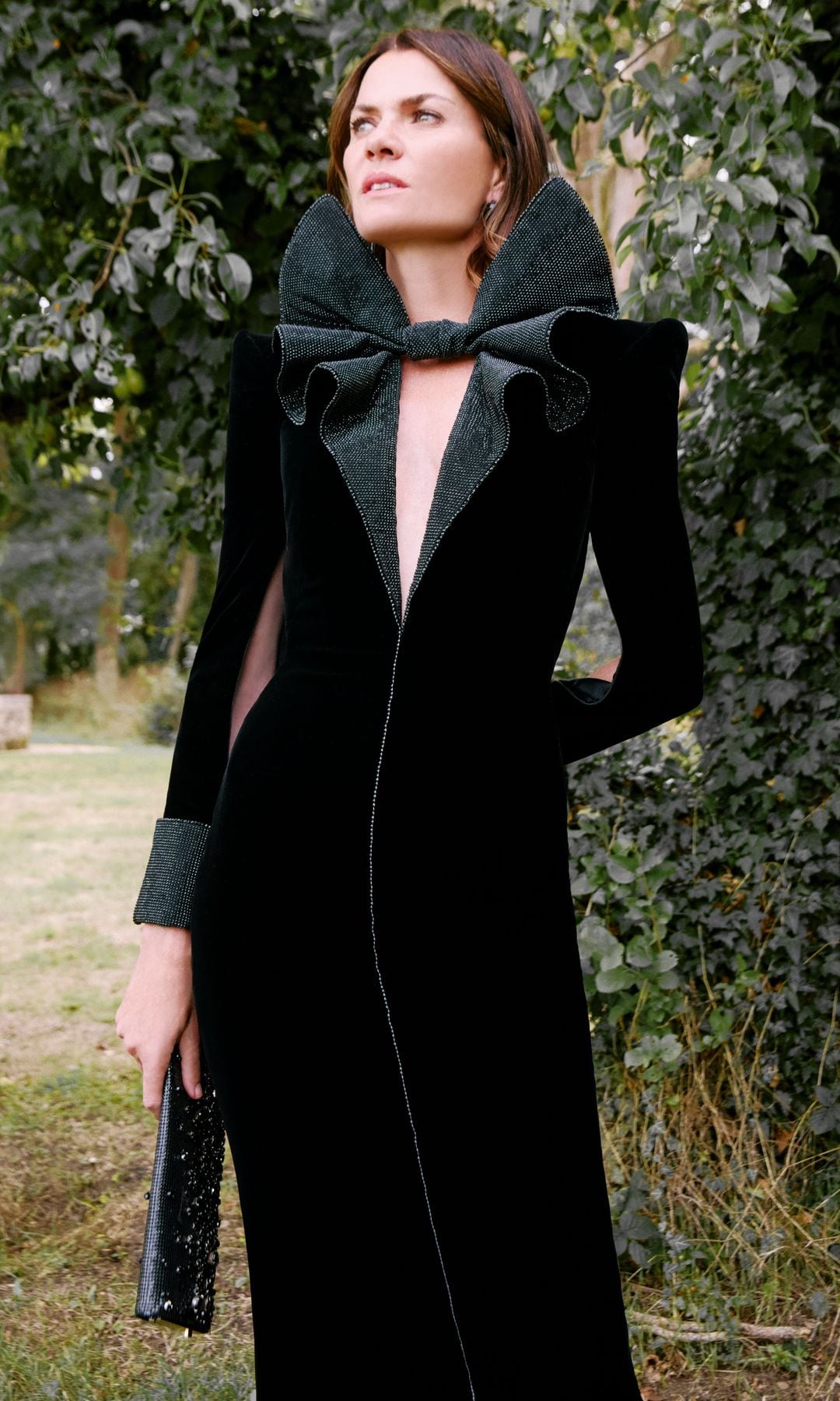 En un bucólico rincón del jardín,  Alejandra de Rojas posa con vestido de terciopelo negro con «strass» y lazo escultórico al cuello, de Giorgio Armani Privé.   Las joyas son de Giorgio Armani