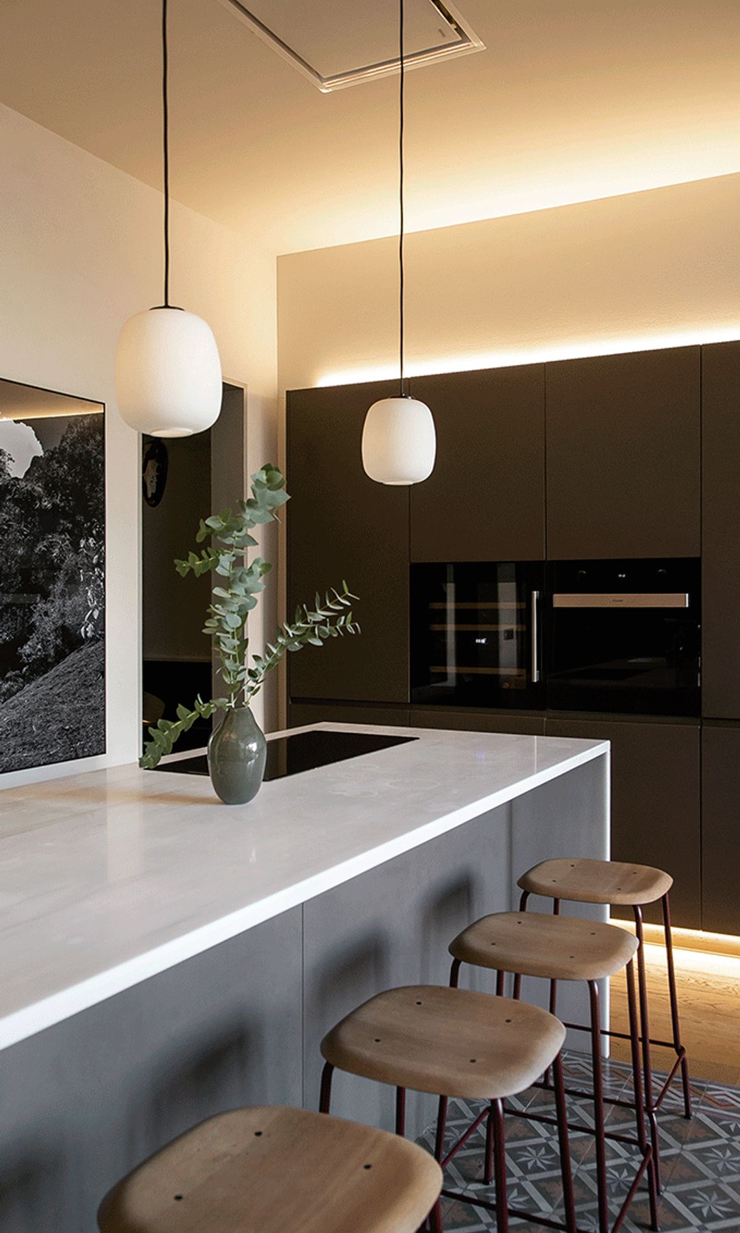 Cocina con isla con taburetes, muebles de cocina de madera oscura, encimera blanca, lámparas de techo, campana de techo 