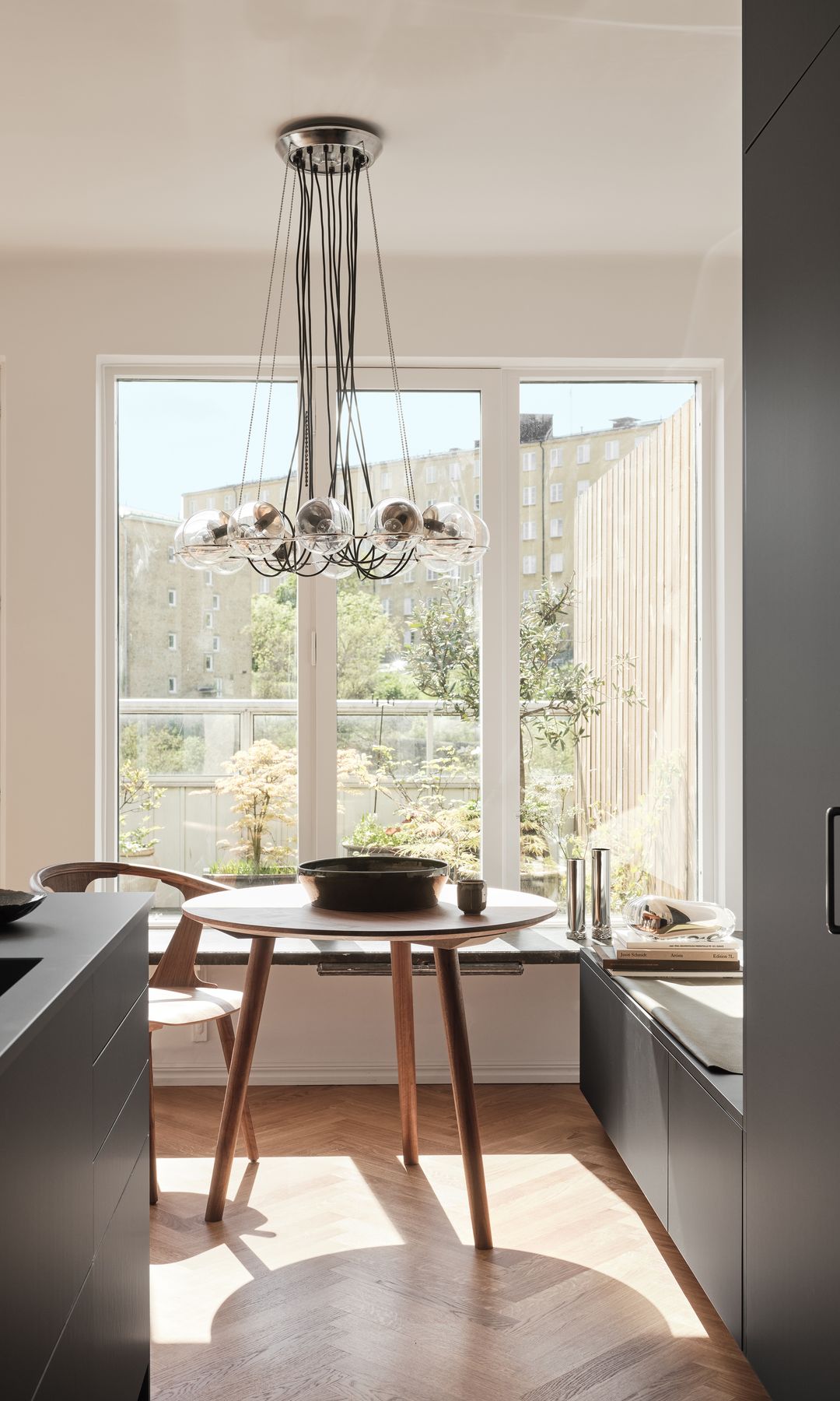 Cocina negra con zona de office junto a la ventana con mesa redonda y banco