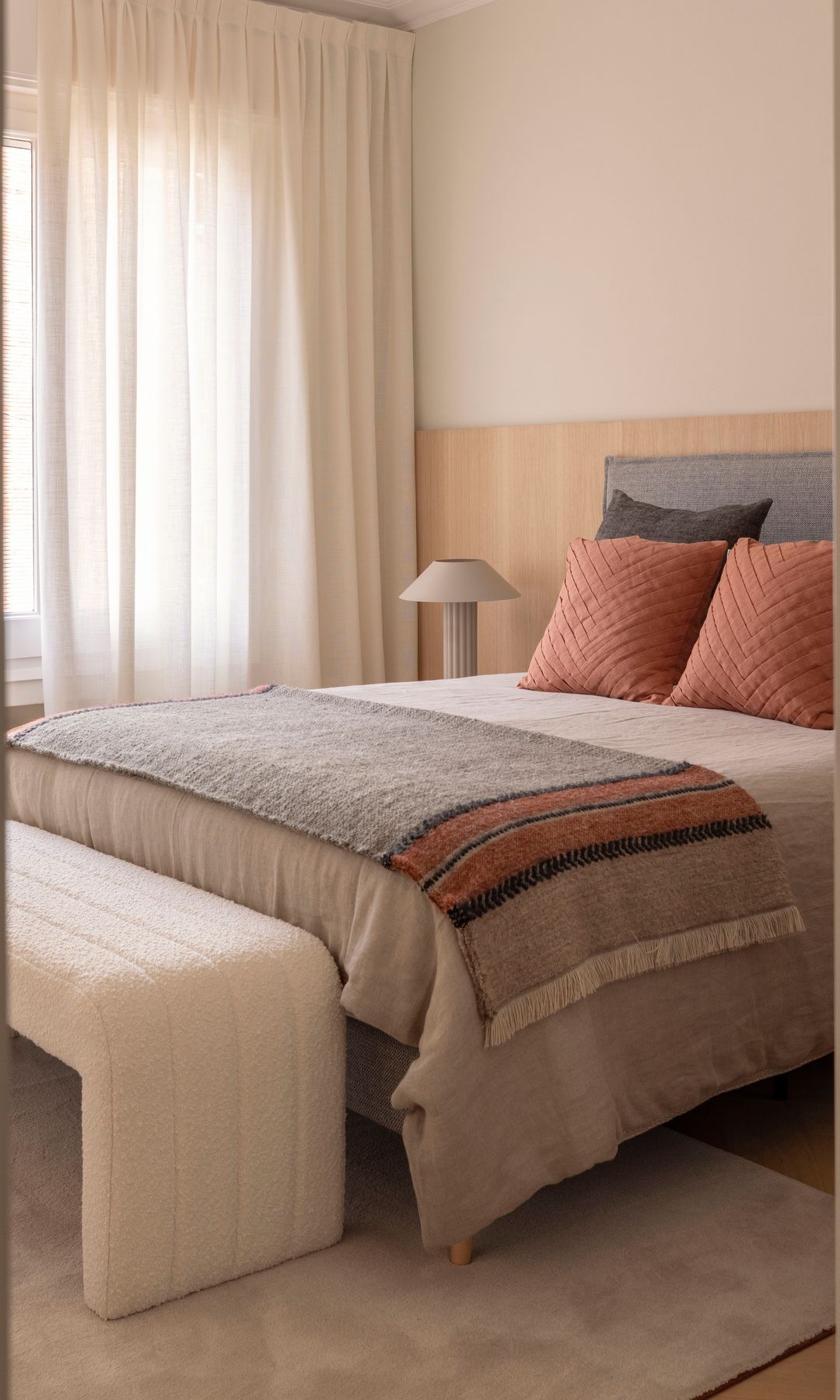 Dormitorio con cabecero entelado, alfombra a los pies de la cama, plaid a los pies, cojines en color caldero, cortinas beiges