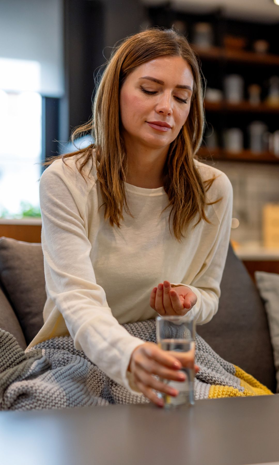 Una mujer con un vaso de agua tomando una pastilla 