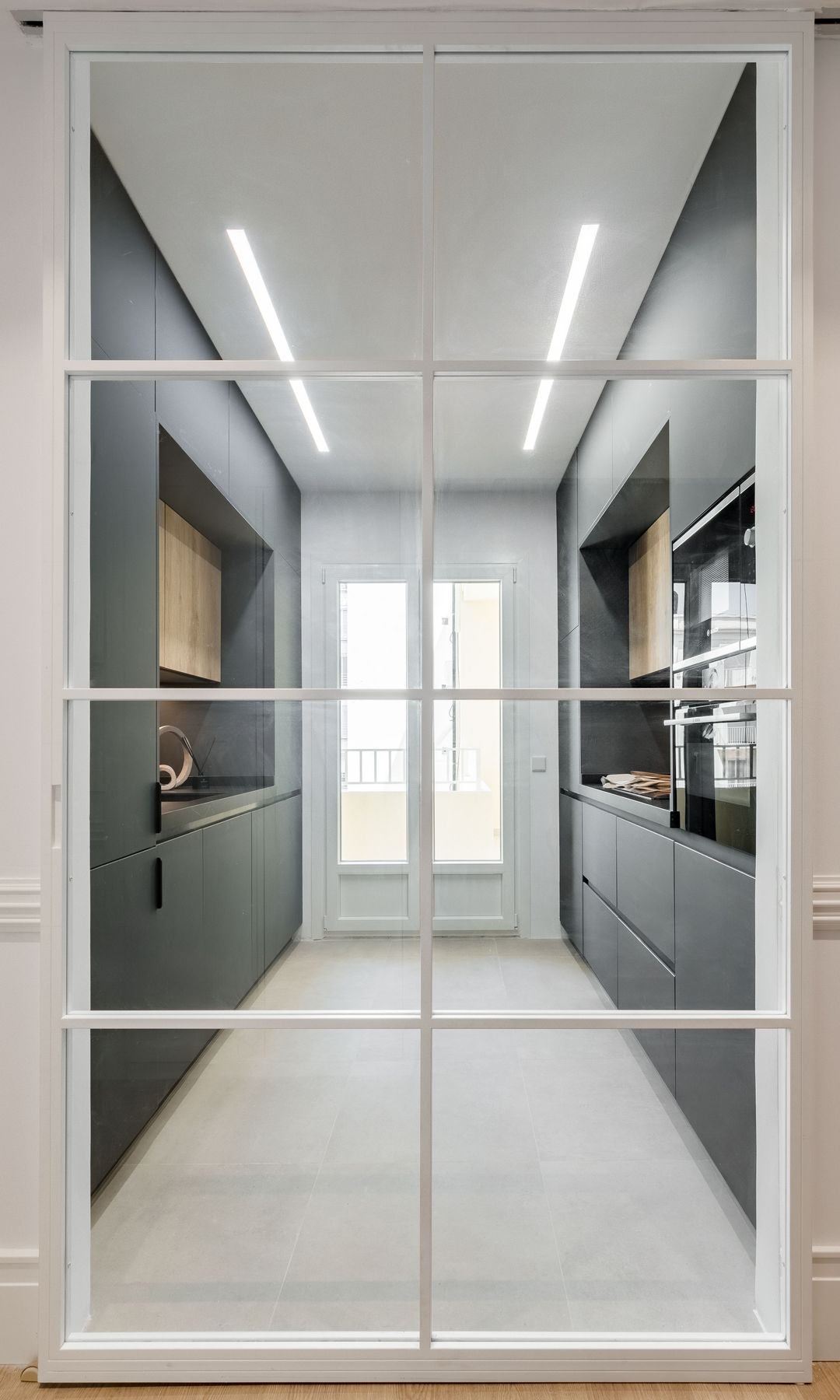 Cocina negra con puerta corredera de cristal, salida a la terraza, armarios hasta el techo, cocina en paralelo