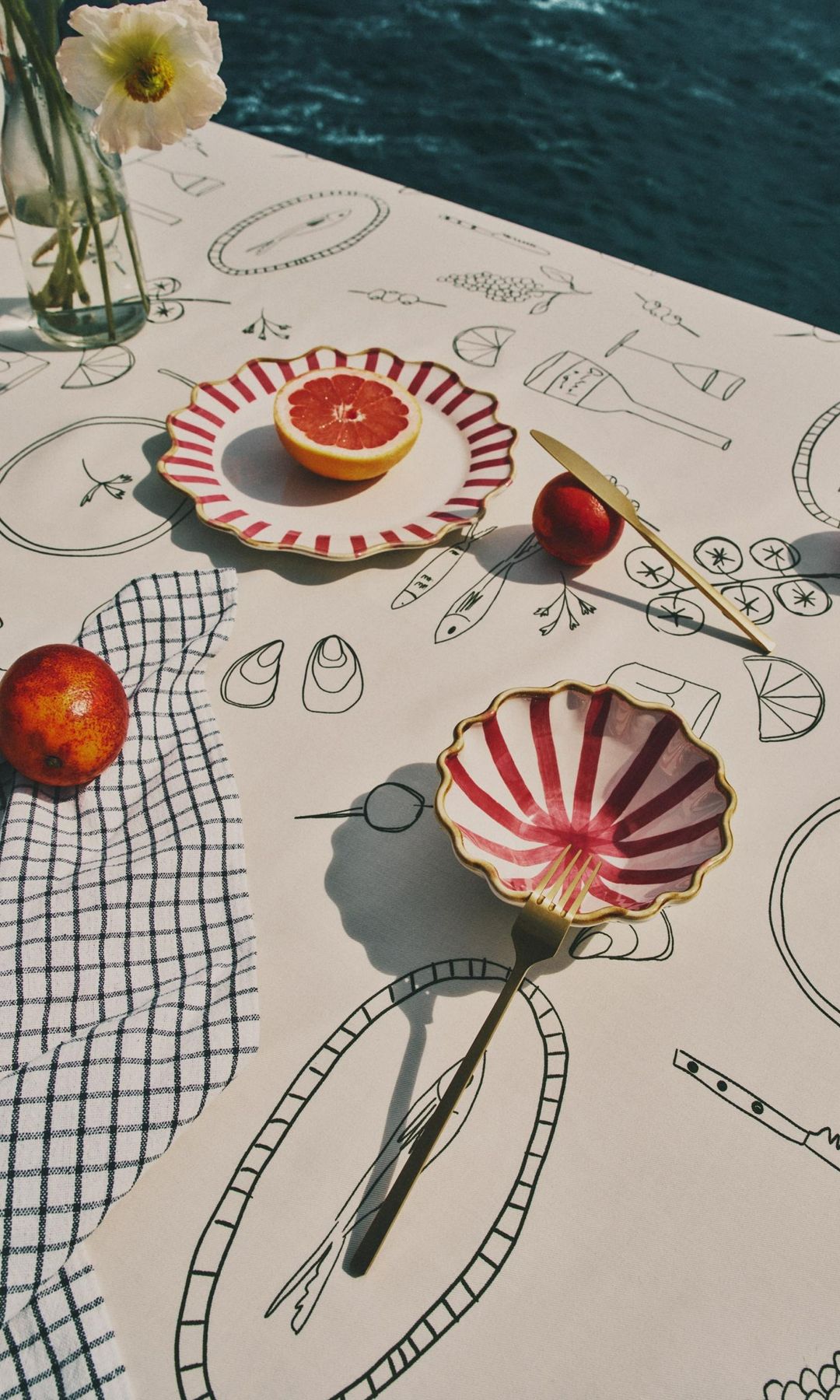 Mesa de verano con mantel con motivos marítimos y vajilla de color rojo y blanco