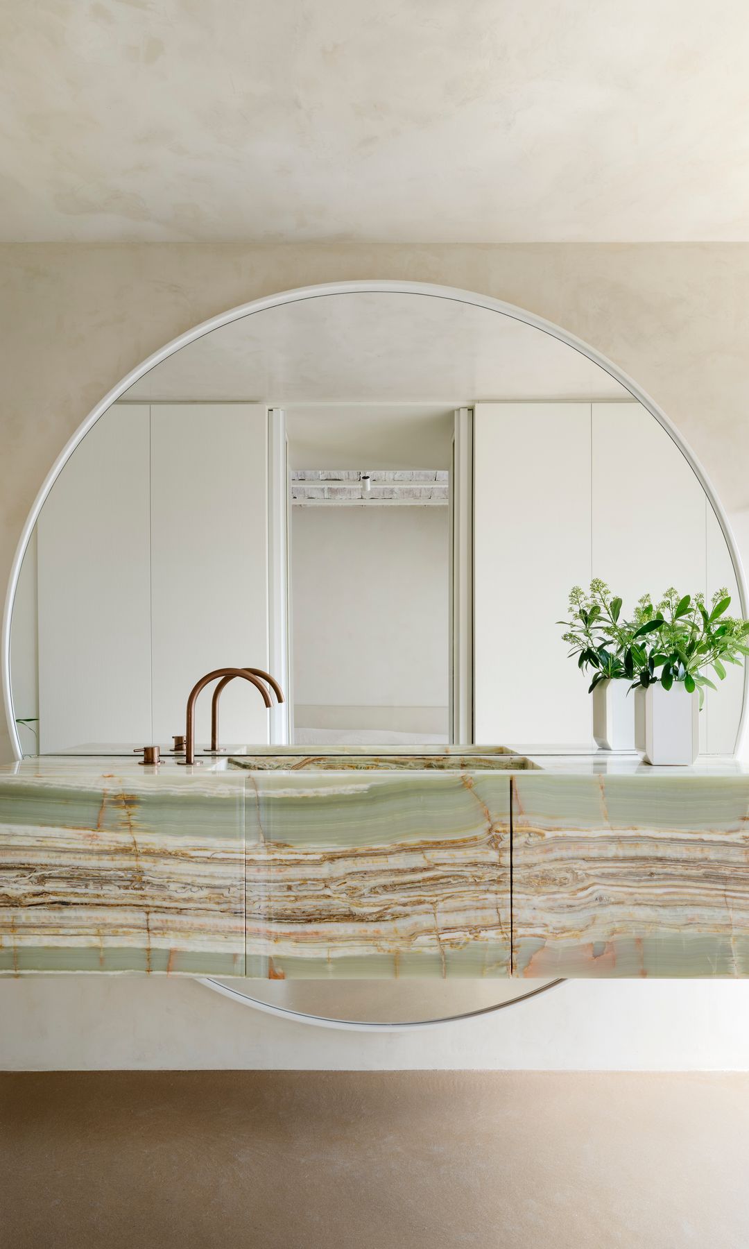 Baño con espejo en arco, mueble y encimera de ónix verde, grifería dorada 