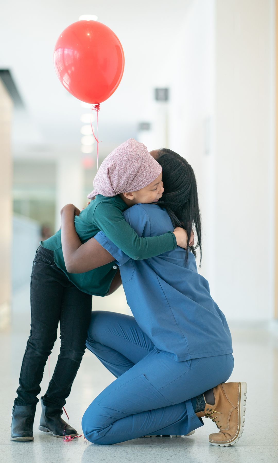 Niño en el hospital con un globo abrazado por su enfermera 