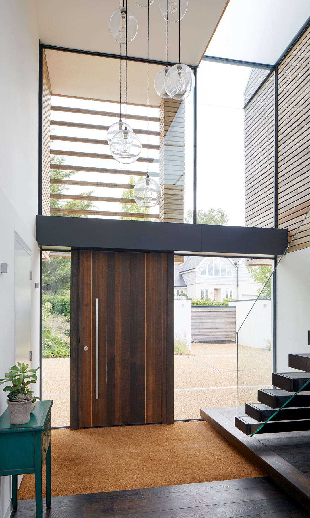 Puerta de entrada de madera con alfombra XL y paredes de cristal 