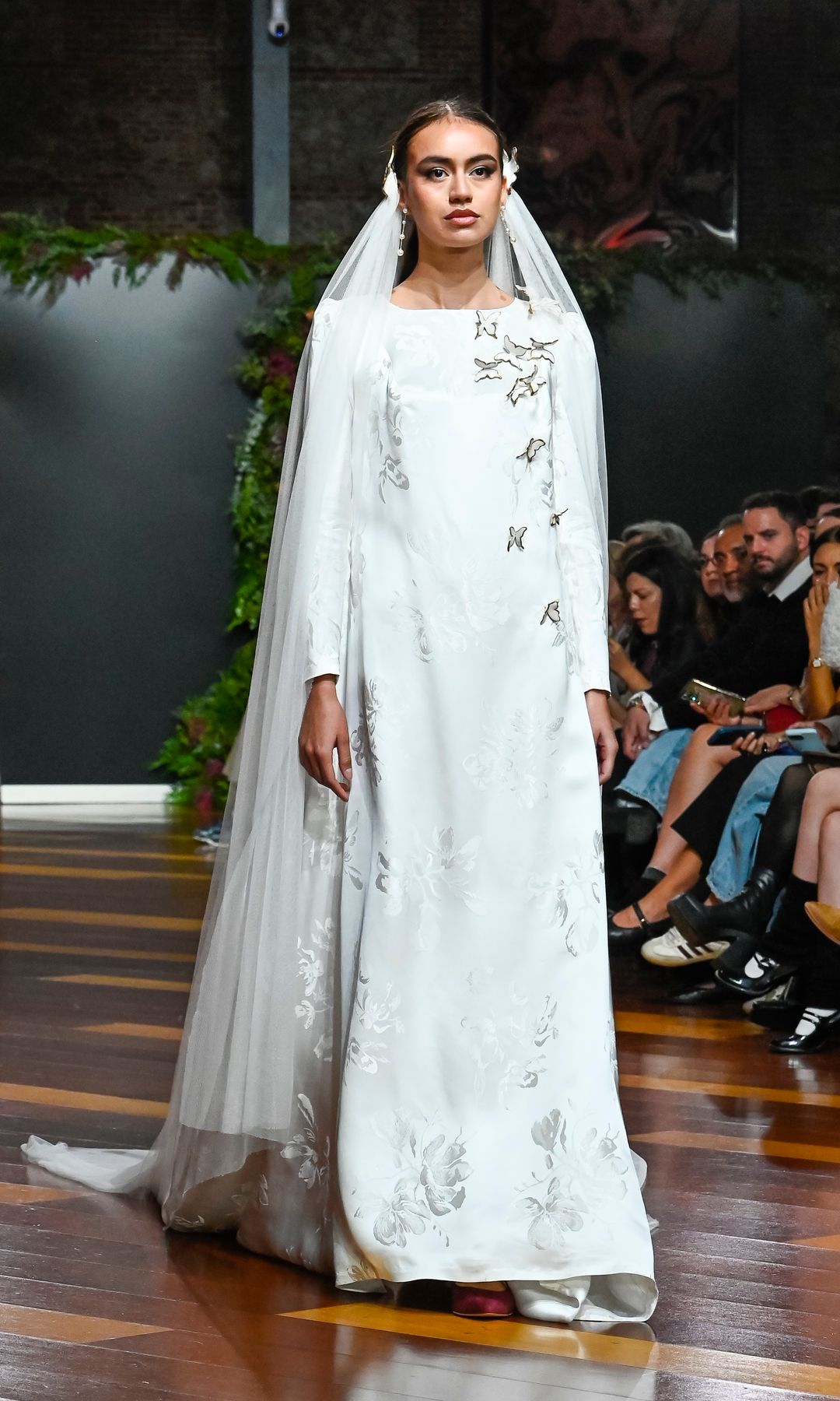 Desfile Carmen Alba durante Atelier Couture con una modelo llevando un vestido de novia de manga larga y velo julieta