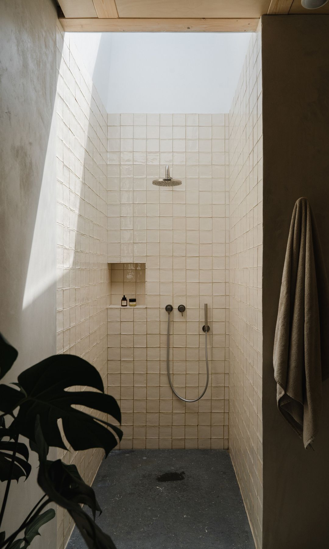 Baño con ducha revestida de azulejos, plato de ducha negro, claraboya