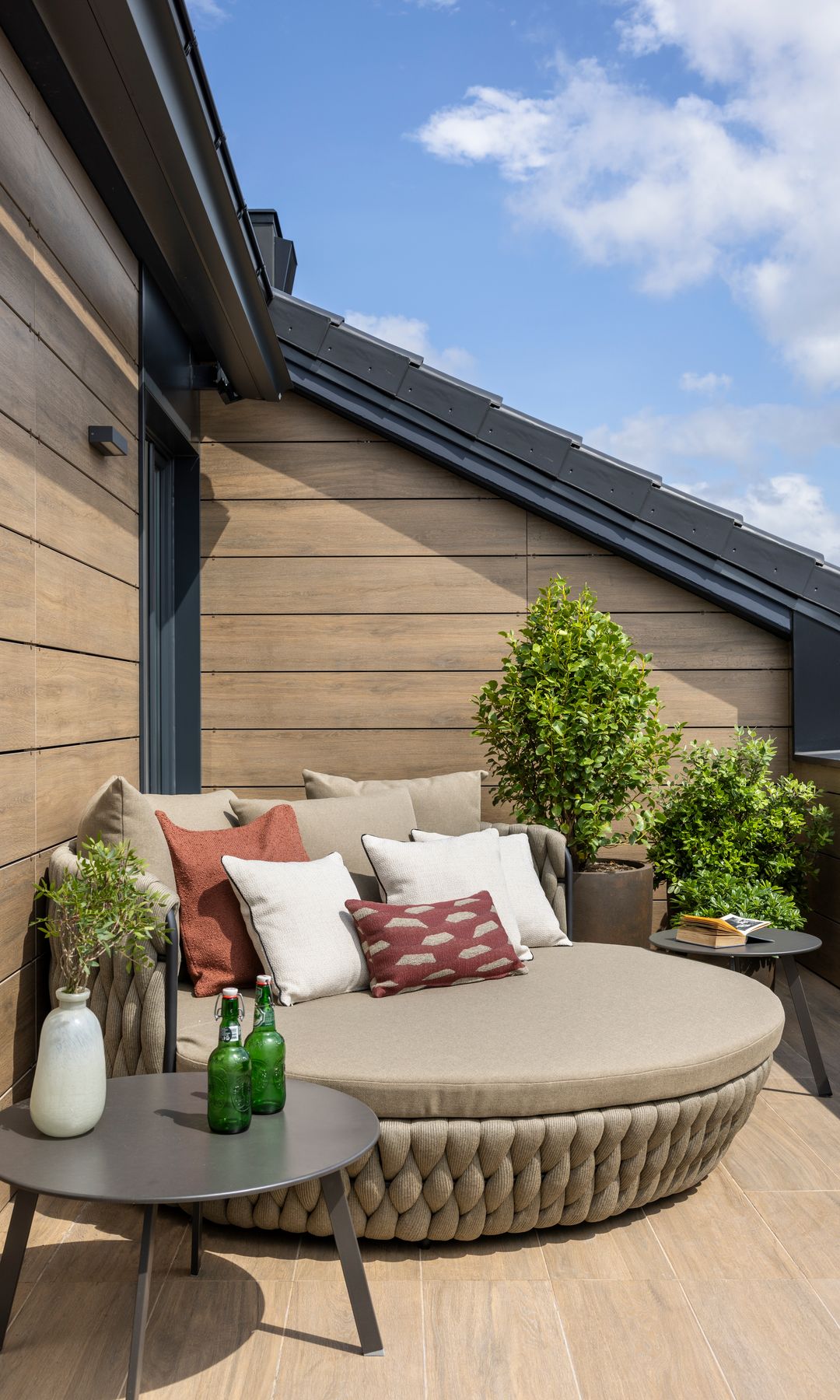 Terraza paredes de madera, cama XL de exterior, plantas, mesas auxiliares