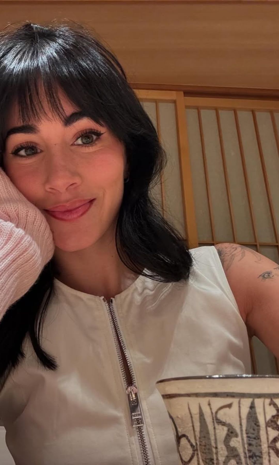 Aitana posa con melena oscura y flequillo mientras toma una bebida.