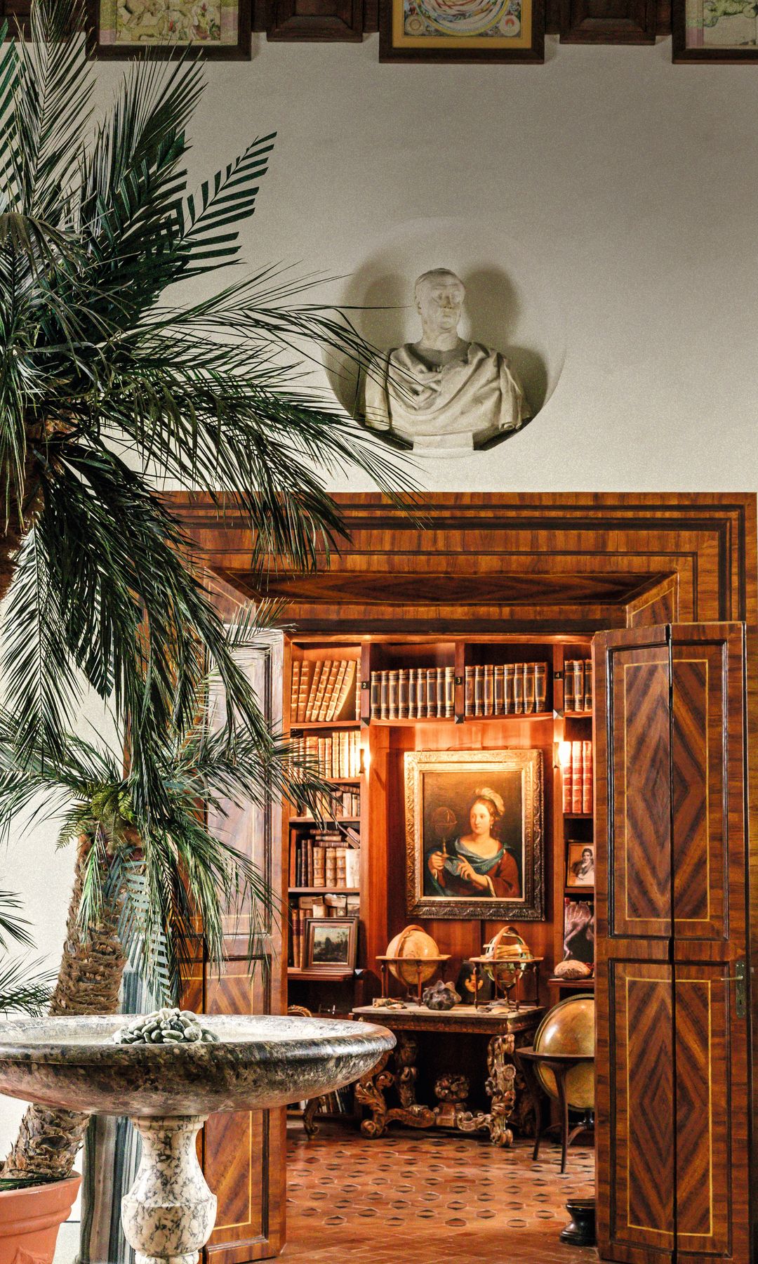 El acceso a la biblioteca, a través de dos puertas de marquetería, desde el recibidor del "palazzo", presidido por una pila bautismal