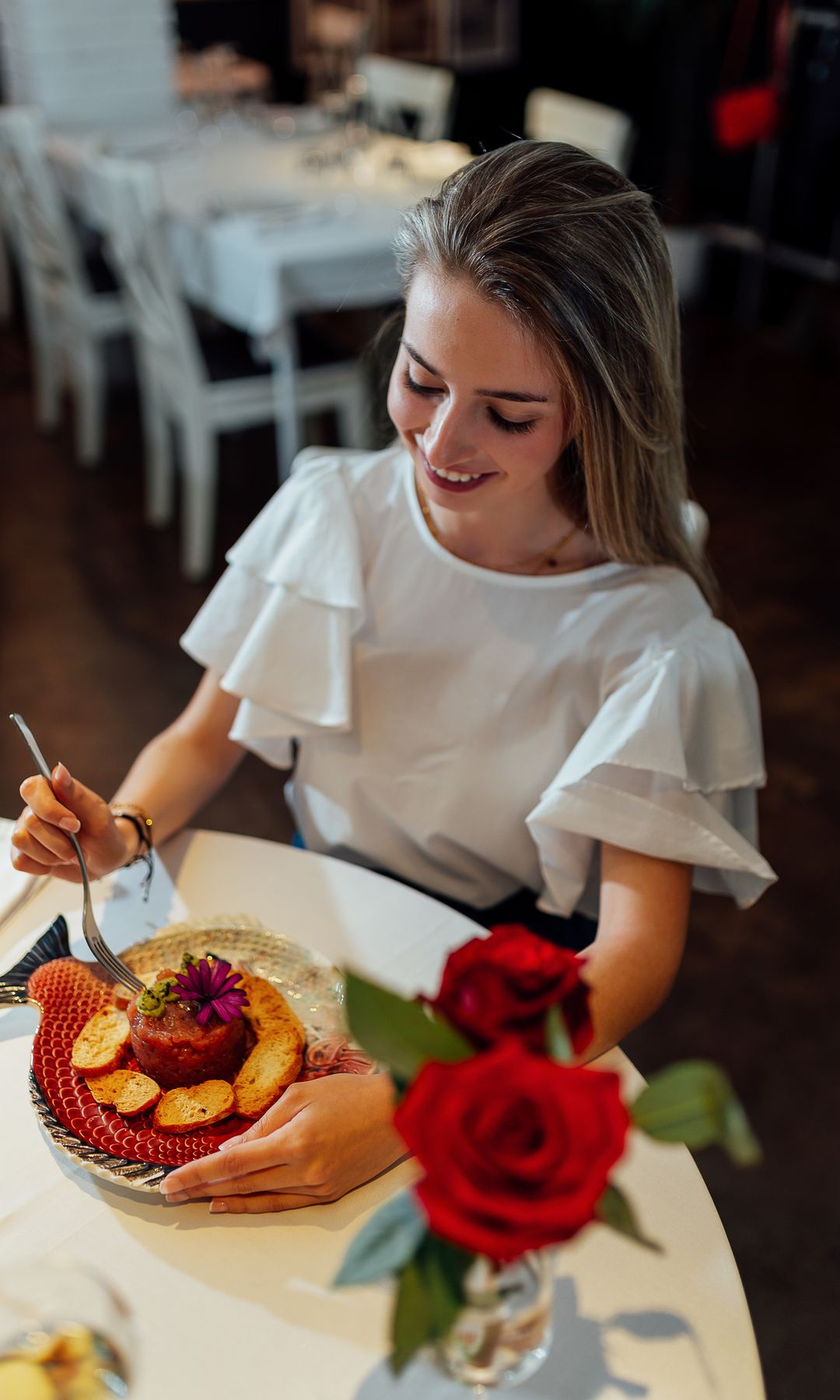 Imagen de una mujer feliz comiendo sano en una mesa decorada con flores