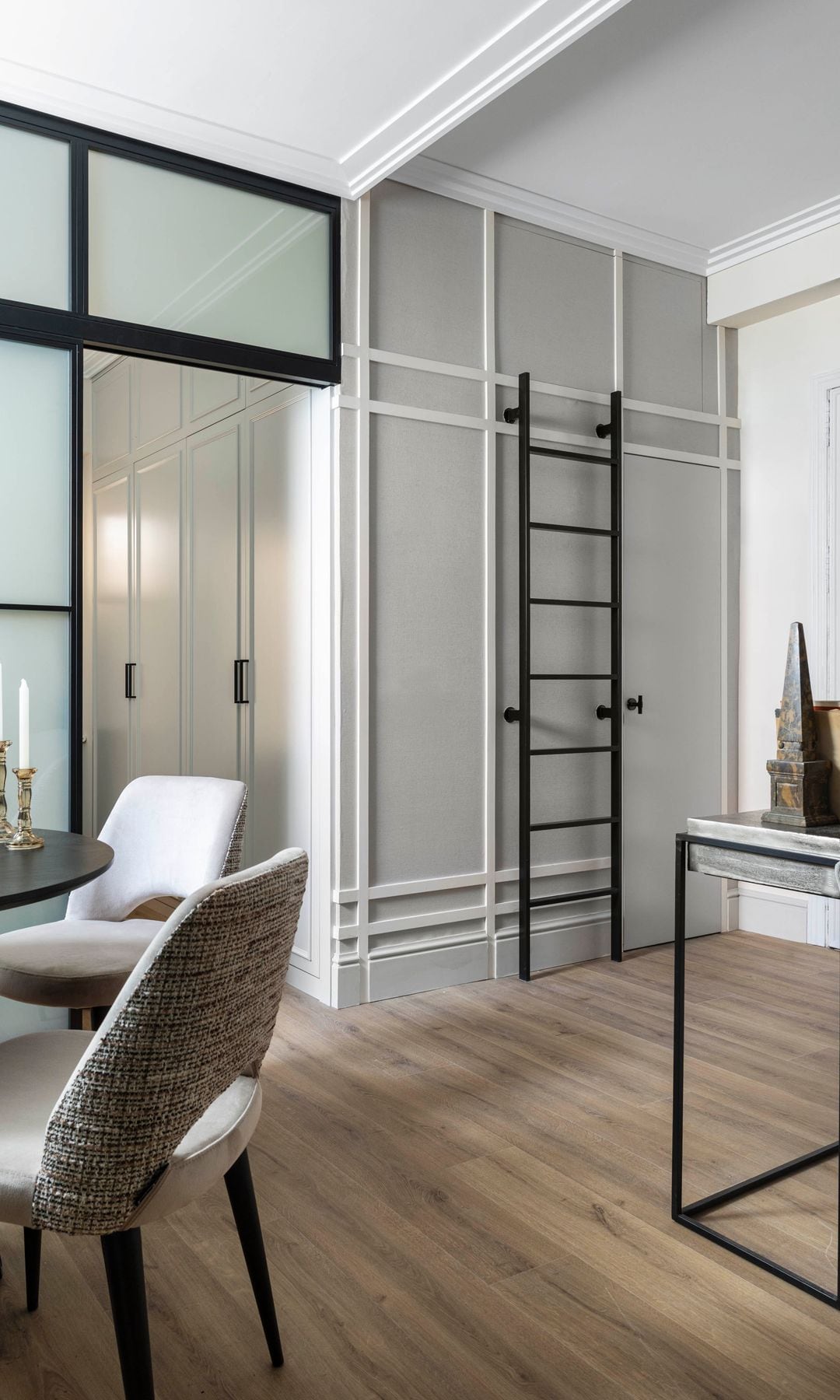 Comedor con altillo con molduras, escalera negra, tabiques de cristal