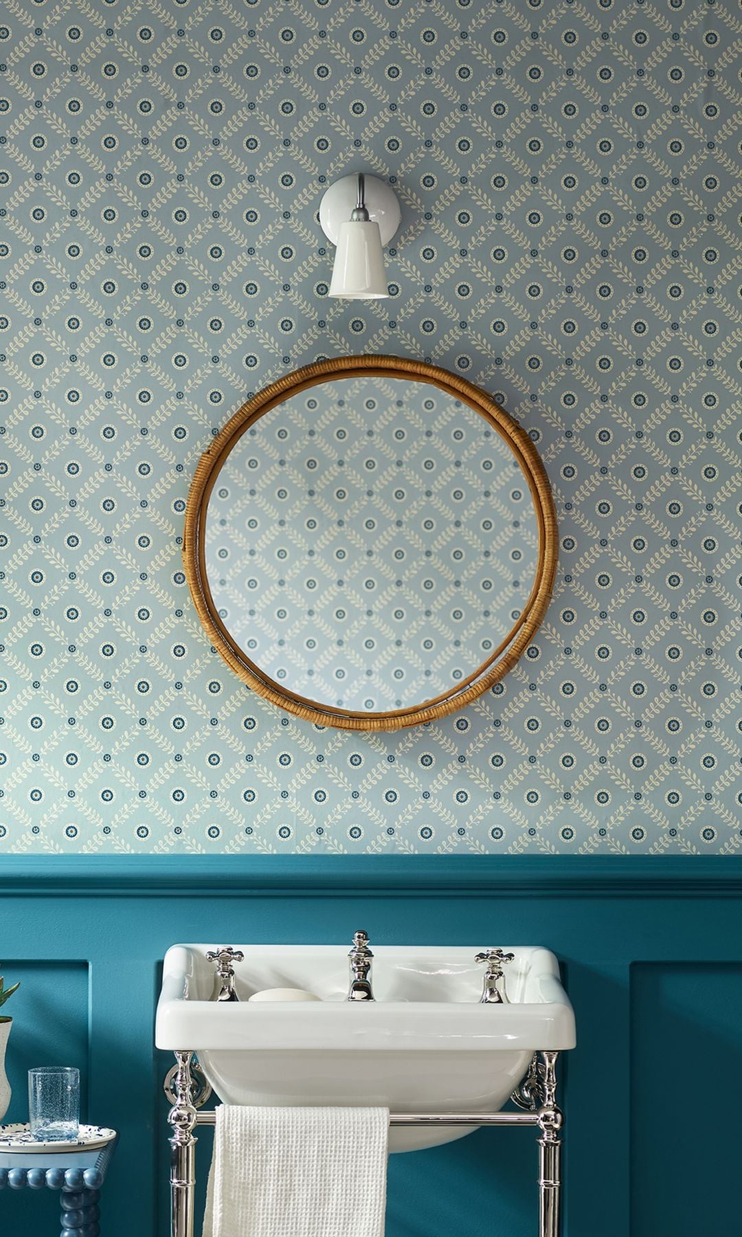 Baño con papel pintado azul, friso de madera azul oscuro, lavabo antiguo y marco dorado