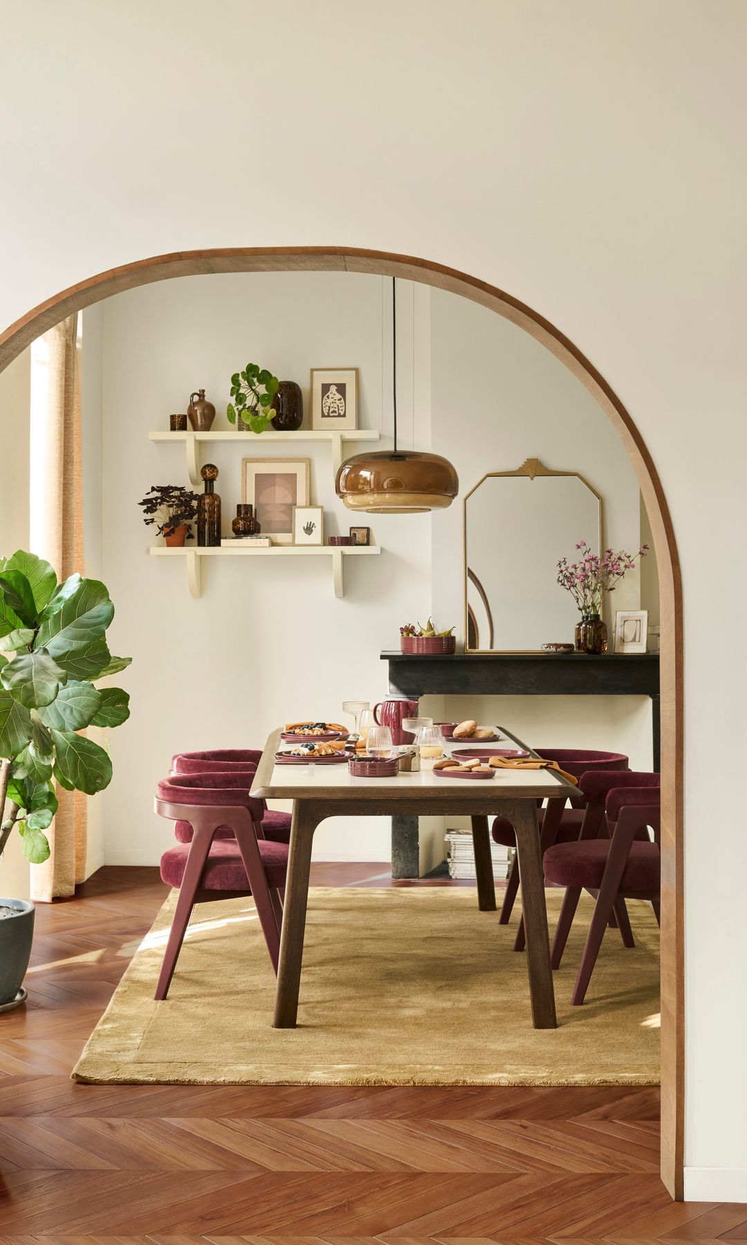 Comedor con chimenea, comunicado con un arco, alfombra de fibras vegetales, sillas tapizadas en burdeos, lámpara de techo 
