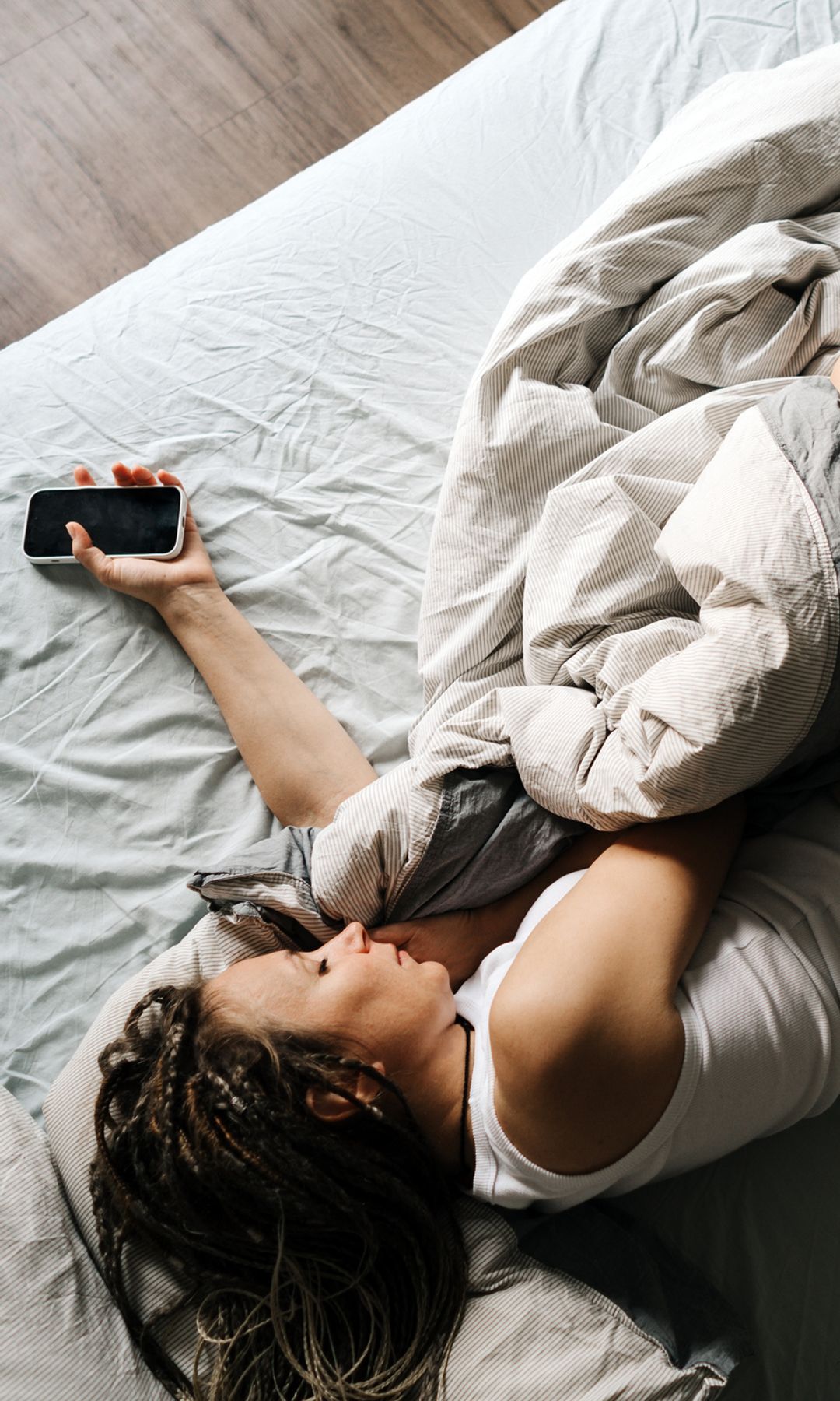 Mujer en la cama con el móvil en la mano