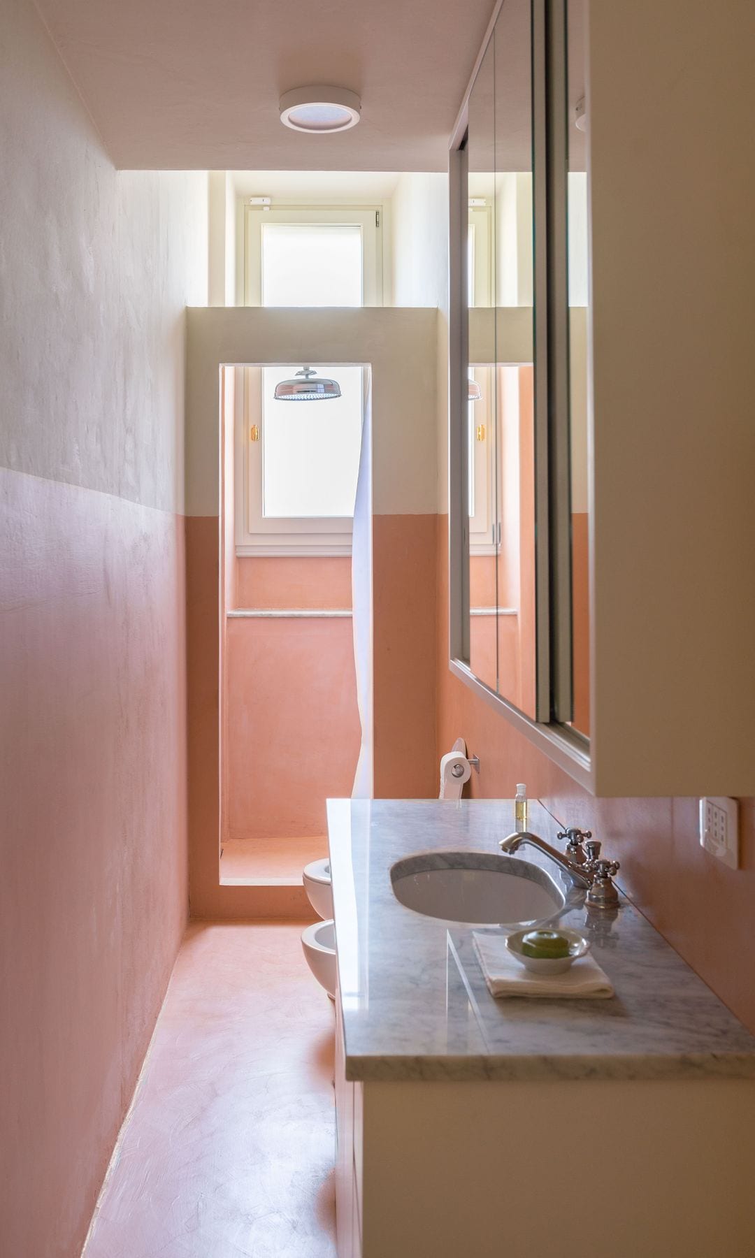 Baño con ducha separada por una puerta de cristal a juego con el zócalo alto de la pared, encimera de granito, lavabo encastrado, sanitario y bidé 