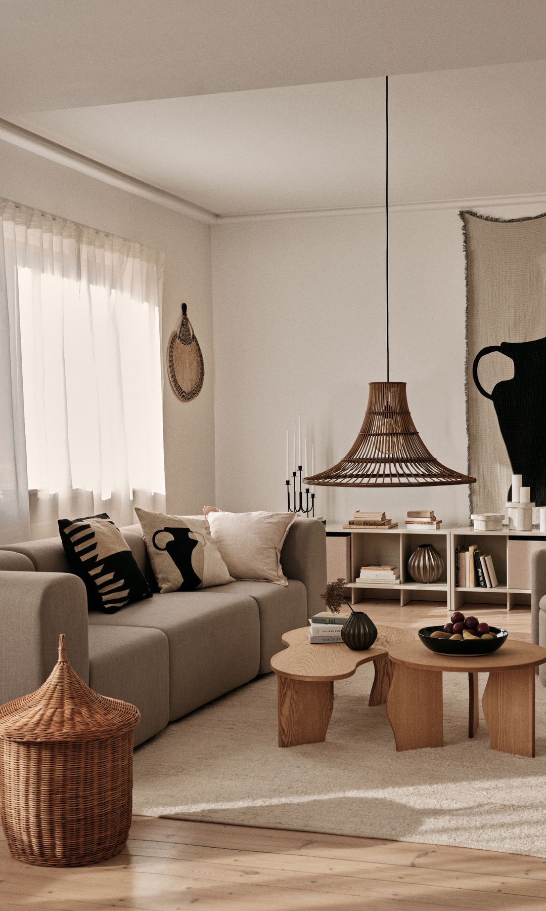 Salón de estilo nórdico con sofá beige, alfombra de fibras vegetales, mueble bajo con estantería, cesto, lámpara de techo de fibras vegetales