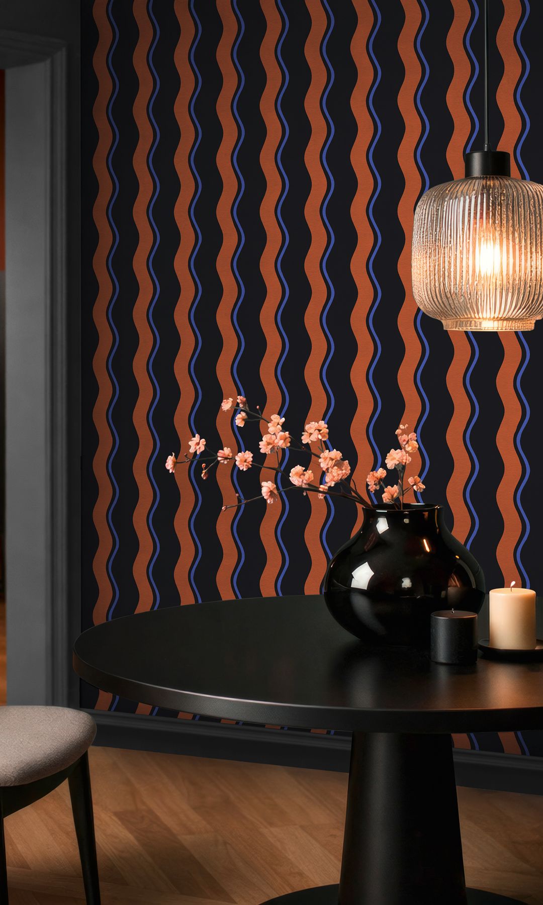 Comedor con papel pintado geométrico en tonos intensos, mesa de comedor negra, lámpara de techo, silla tapizada 