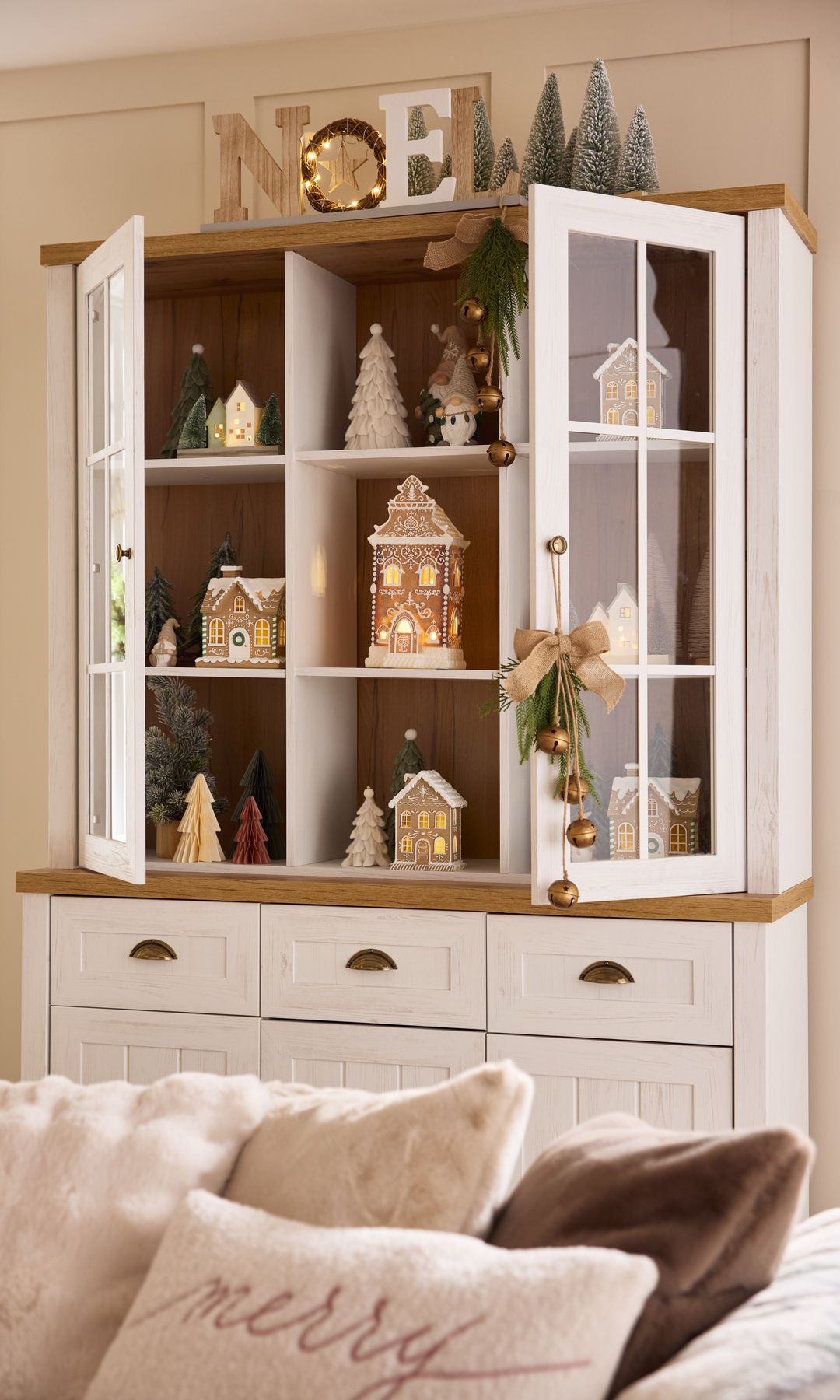 Salón con sofá blanco y alacena con vitrina superior con adornos de Navidad 