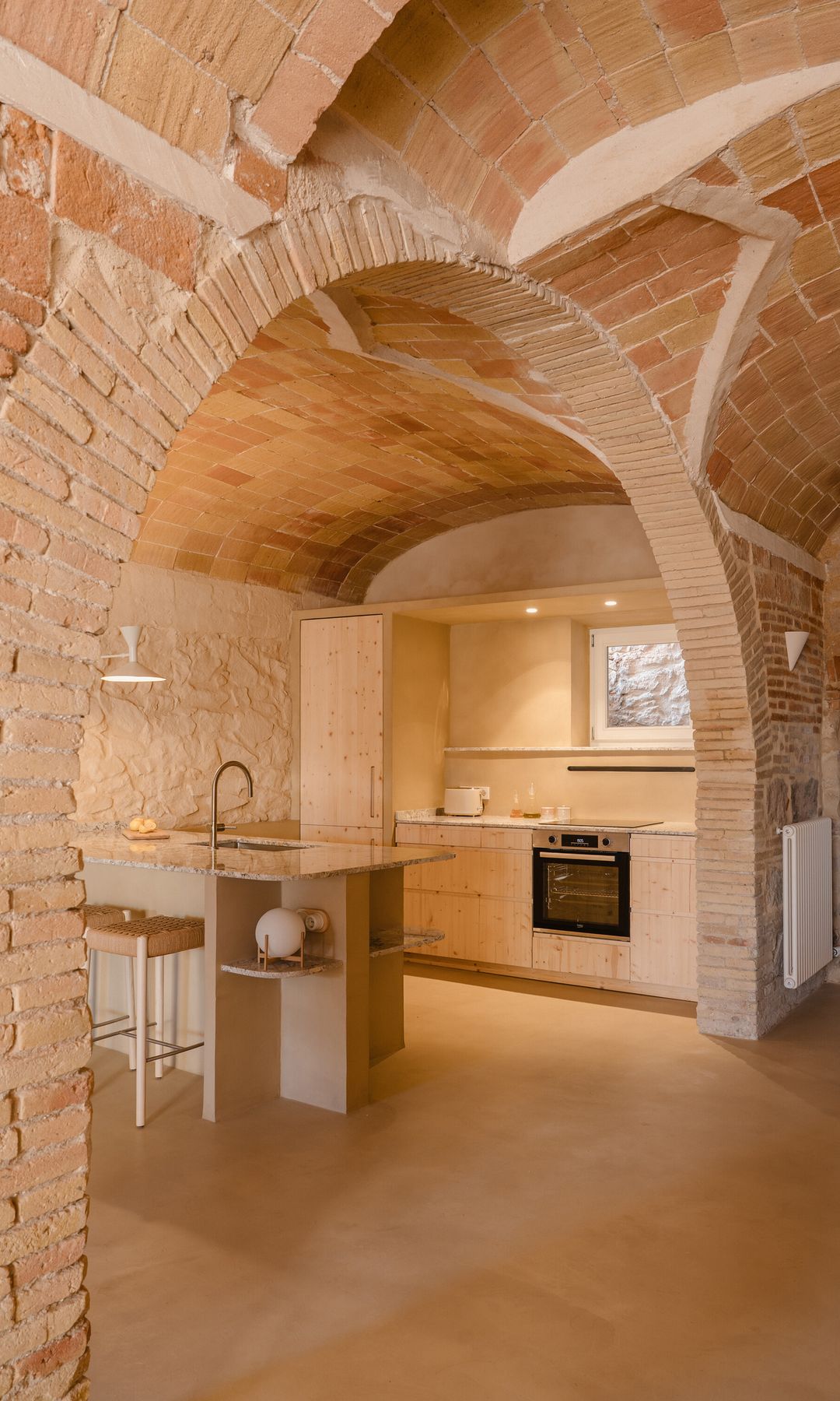 Cocina con isla, bóvedas catalanas en el techo, cocina de madera clara