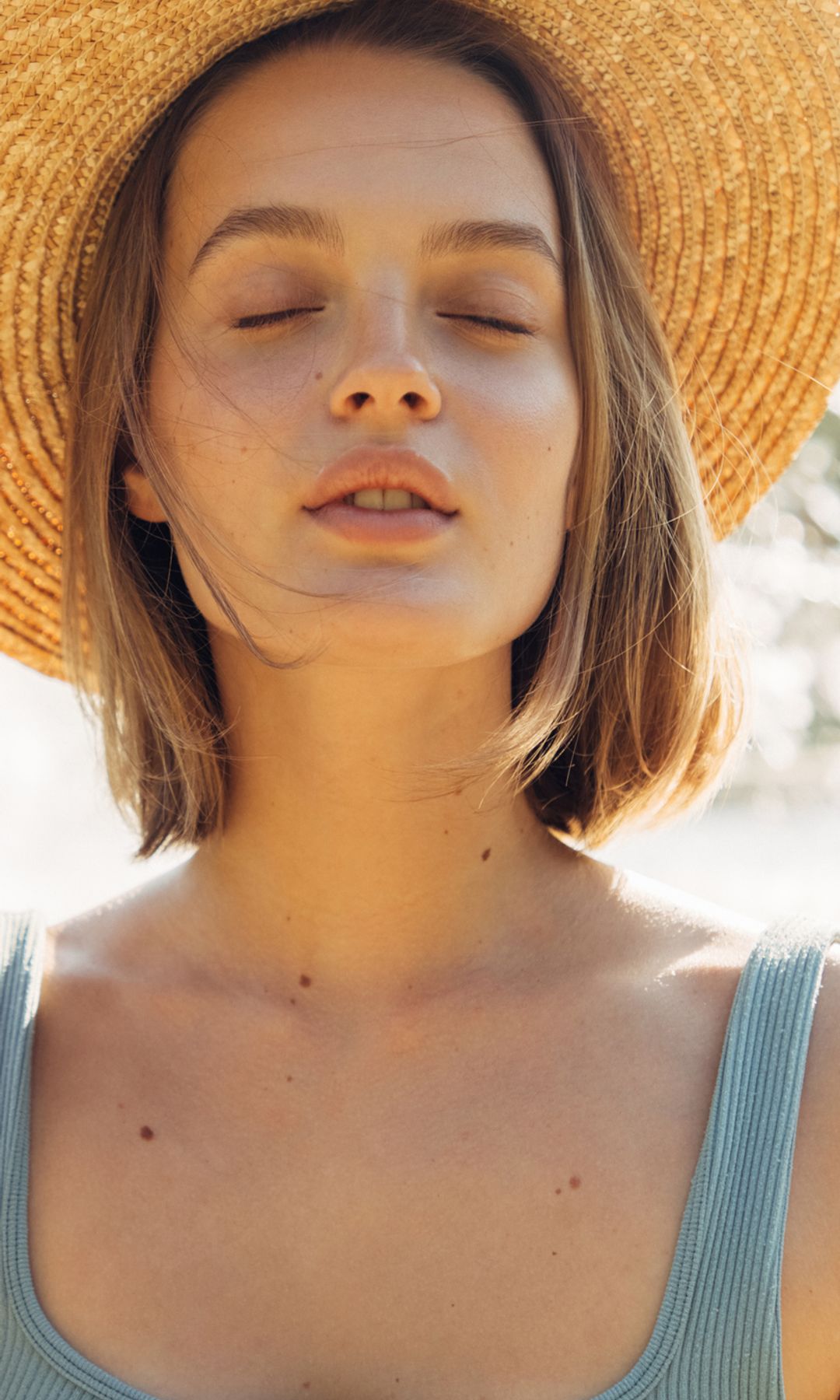Mujer con la cara descansada y con un sombrero en verano