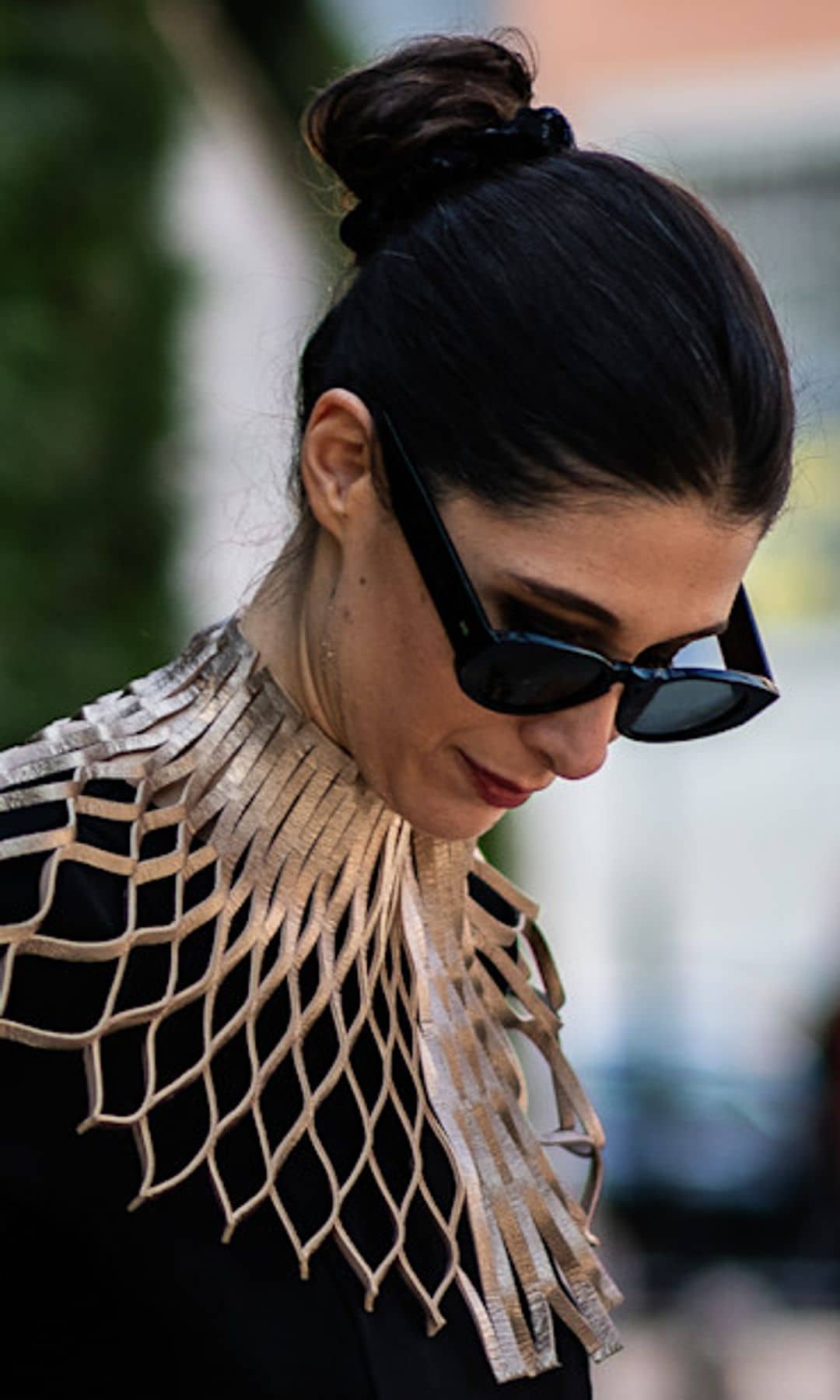 Invitada con vestido negro, moño alto y gafas de sol