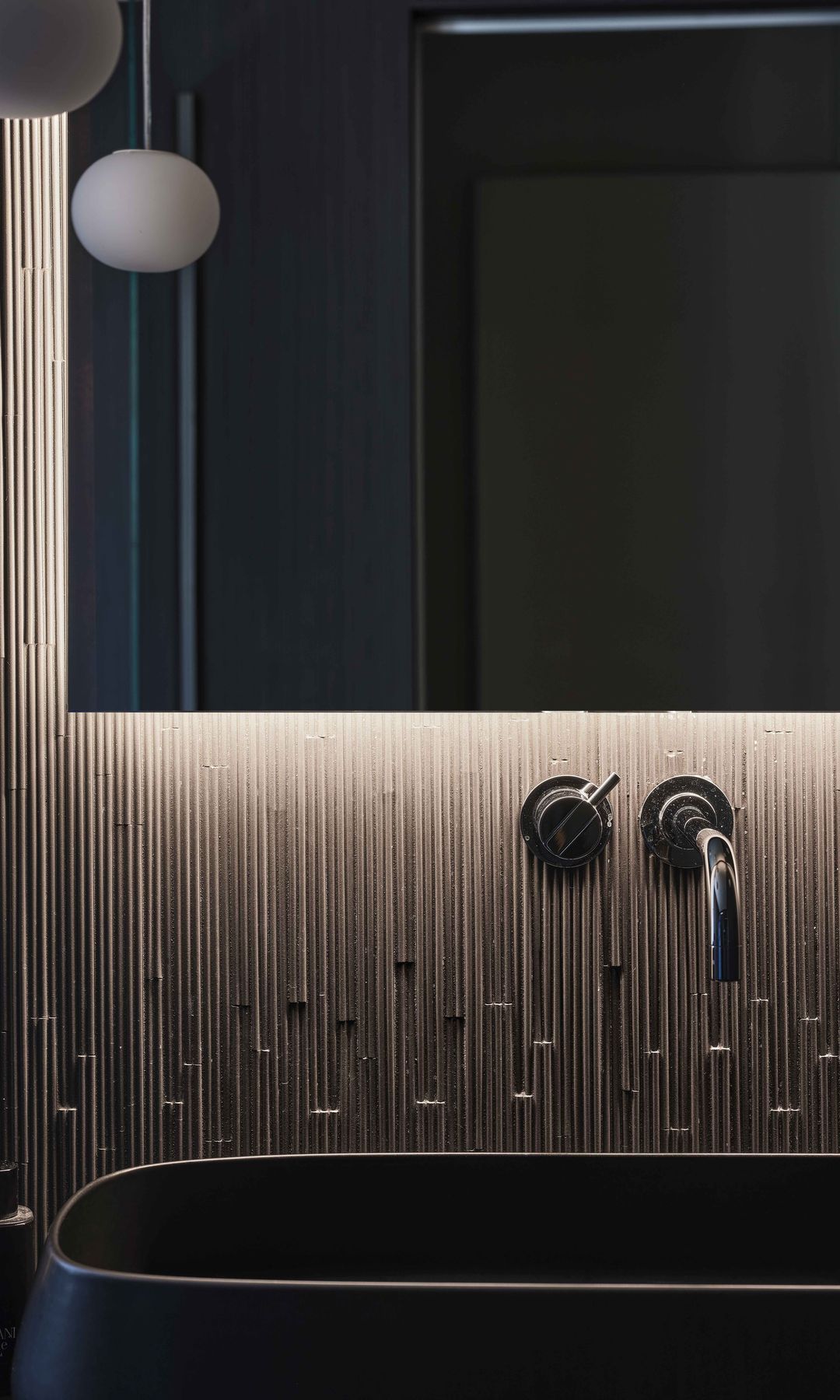 Baño en color negro, con revestimiento marrón grifería negra