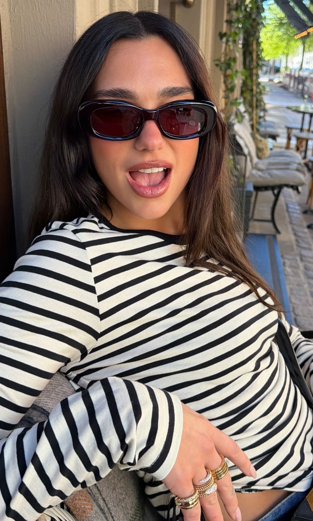 Dua Lipa sentada en una cafetería de Copenhague con camiseta de rayas y gafas de sol