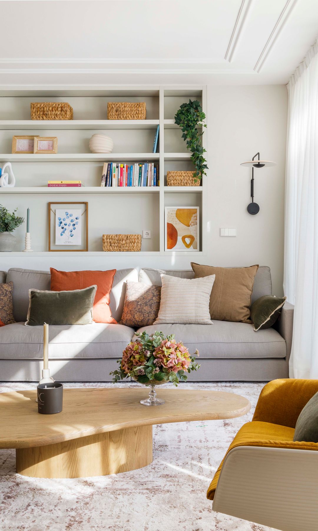 Salón con estantería a medida en la pared del sofá, sofá gris, mesa de centro de madera