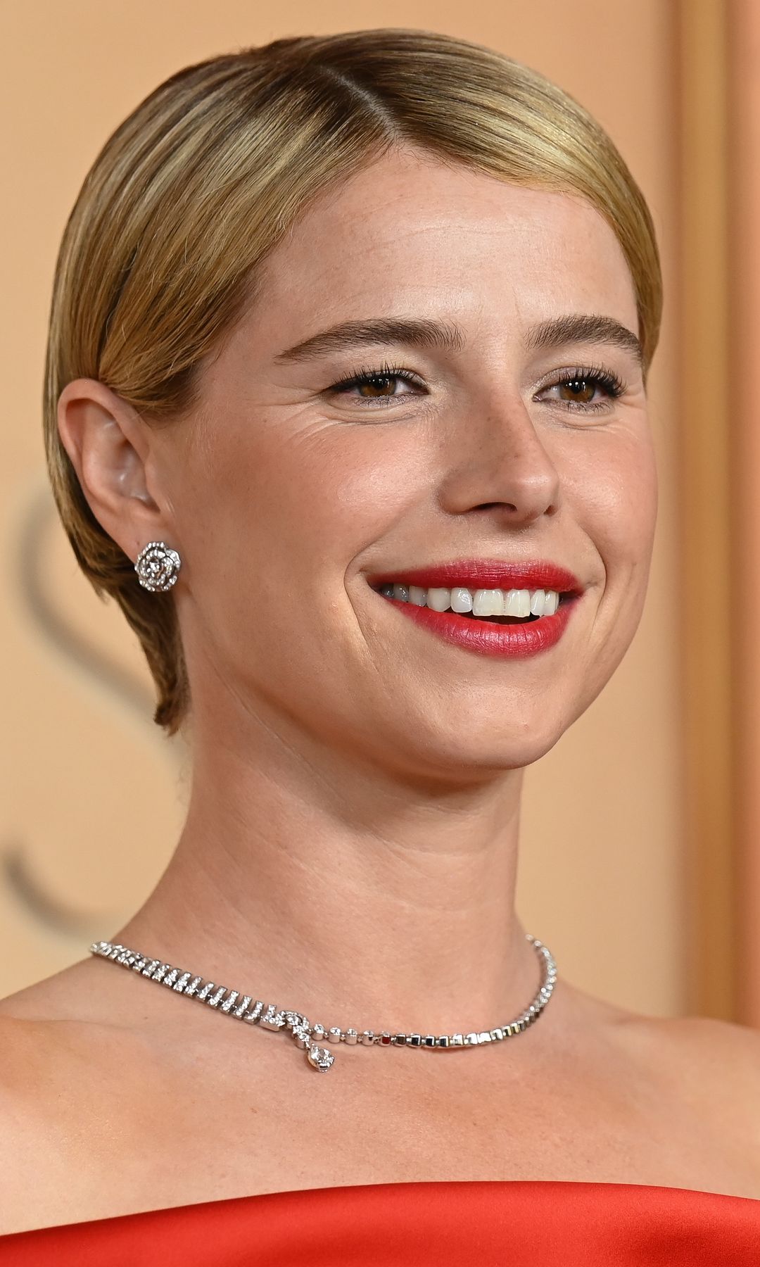 Jessie Buckley en los premios Oscar 2026 con pelo corto, joyas de brillantes y labial rojo