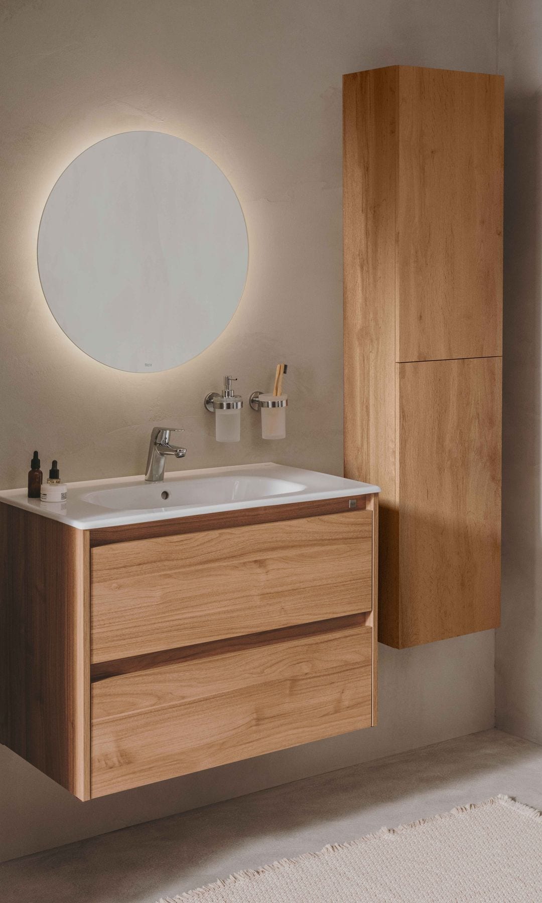 Baño con mueble bajolavabo y armario de madera, lavabo empotrado, espejo redondo y accesorios colgados en la pared