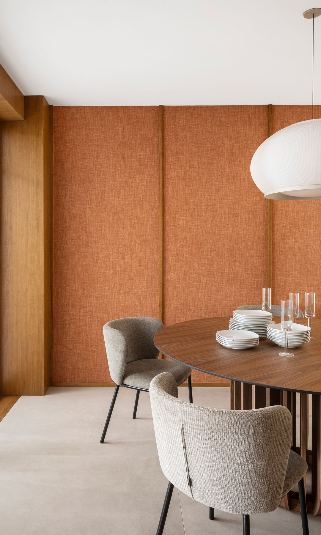 Comedor con paredes con textura marrón, mesa de madera, sillas tapizadas, alfombra y lámpara blanca