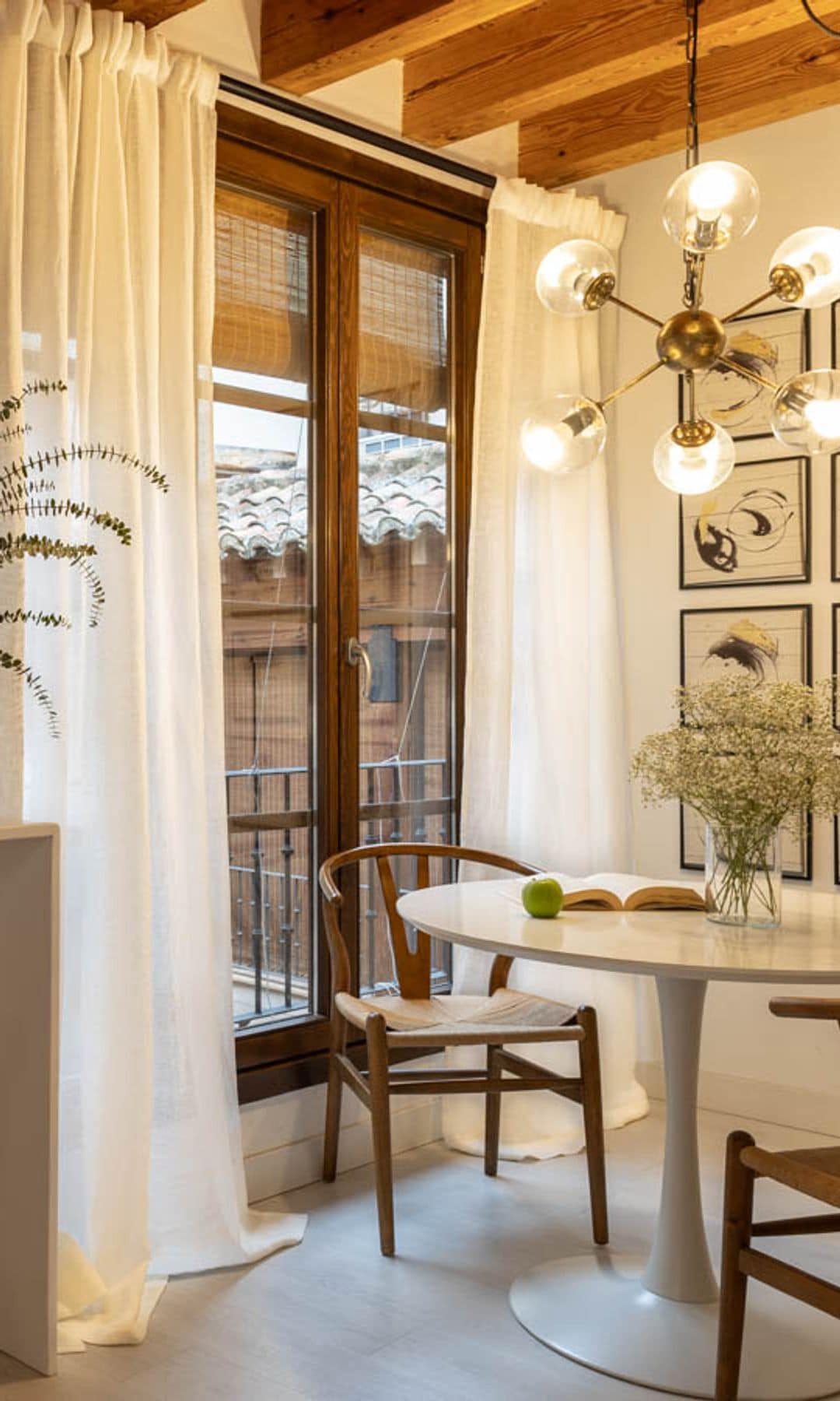 Comedor con mesa Tulip, cuadros en la pared, lámpara de techo, barra con taburete, ventana salida al balcón, cortinas blancas
