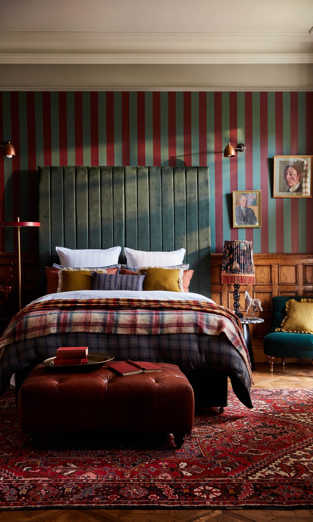 Dormitorio con cabecero alto, papel pintado de rayas, alfombra, ropa de cama de cuadros, friso de madera oscura