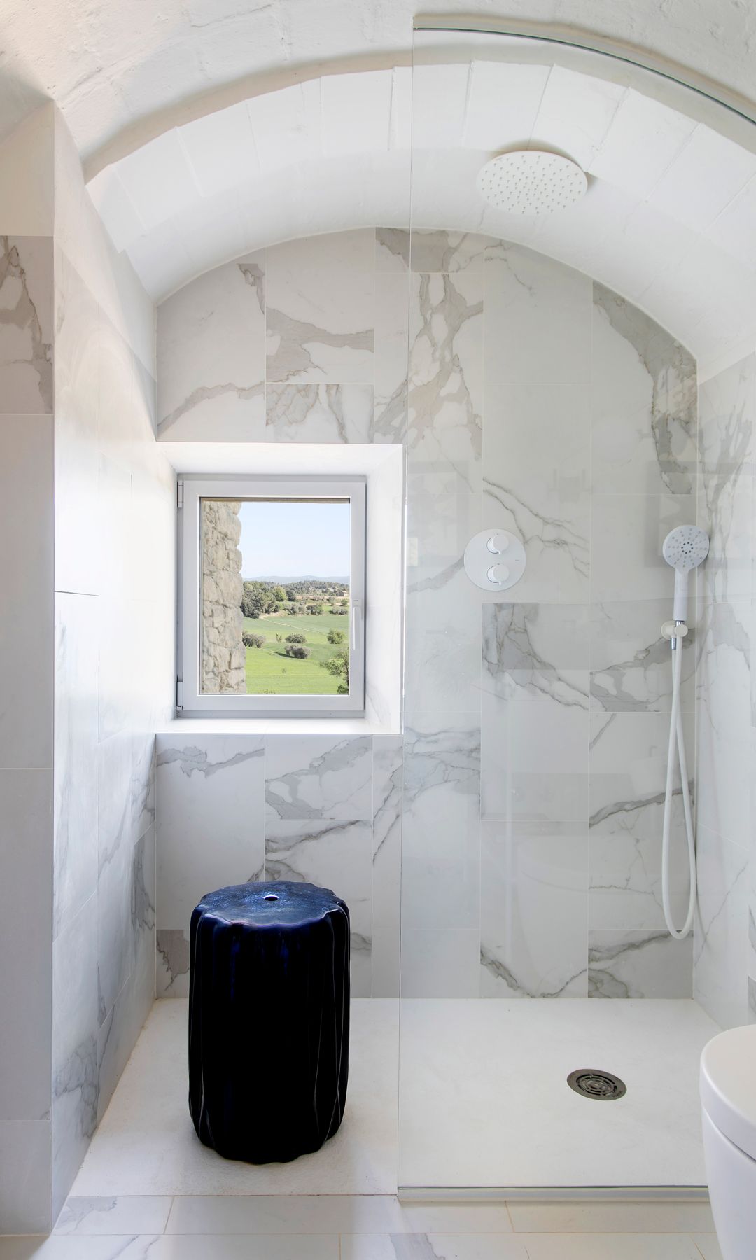 Ducha a ras de suelo con revestimiento de mármol, ventana techo en forma de arco