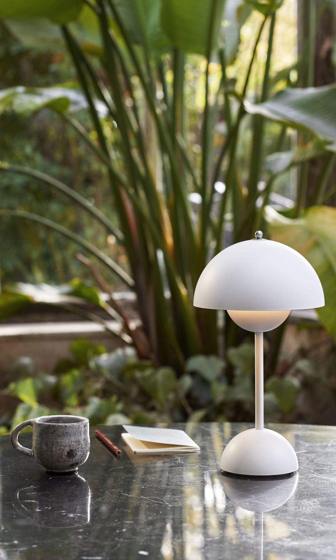 Lámpara portátil blanca sobre una mesa de comedor en el jardín 