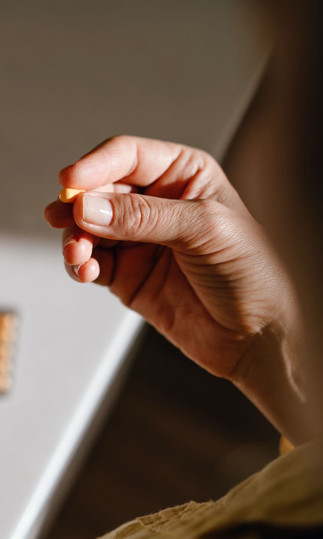 Una mujer sosteniendo una cápsula de vitaminas o complementos alimenticios