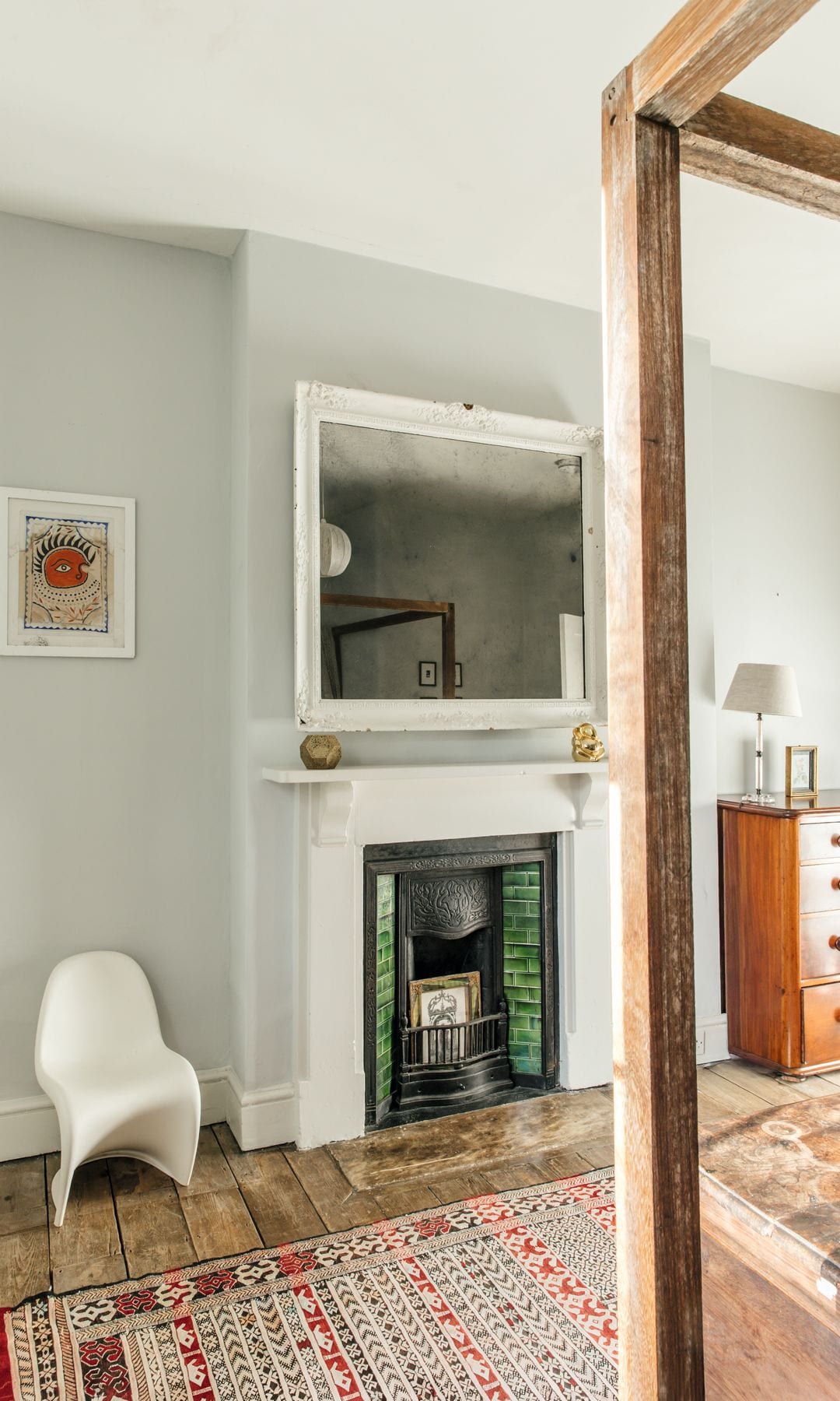 Sala con chimenea, silla blanca, alfombra decorativa y espejo grande