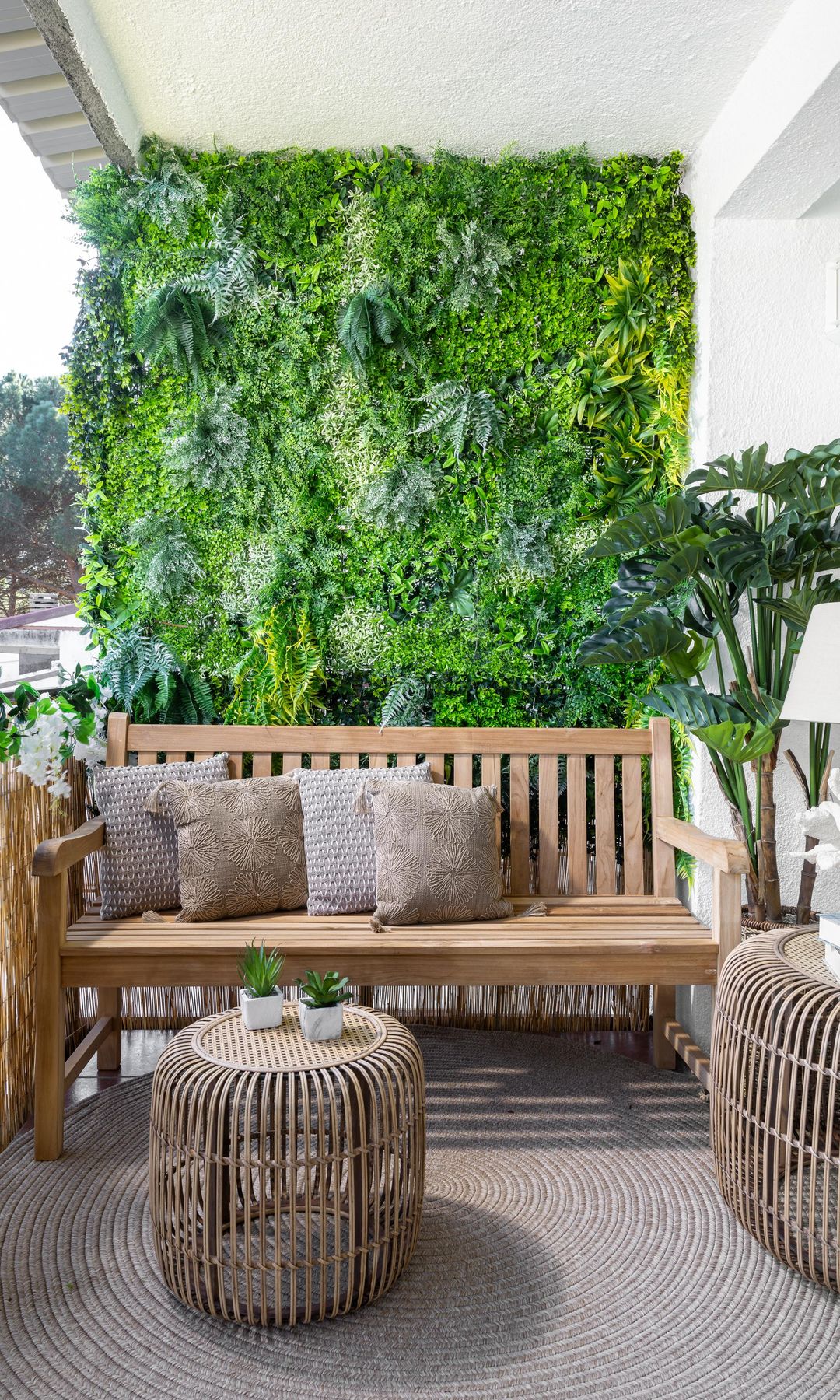 Terraza con banco de madera, jardín vertical, alfombra, mesa de centro de fibras vegetales