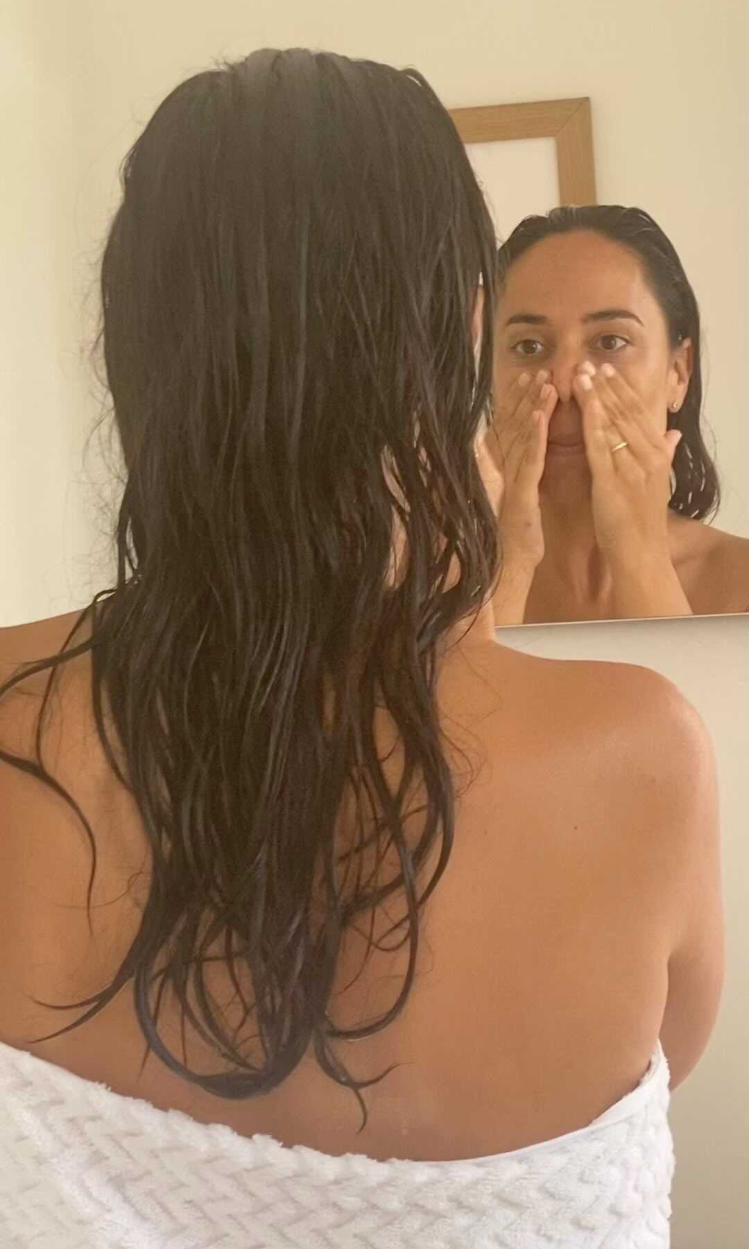 Mujer aplicándose un producto facial frente al espejo durante su rutina diaria de cuidado de la piel.