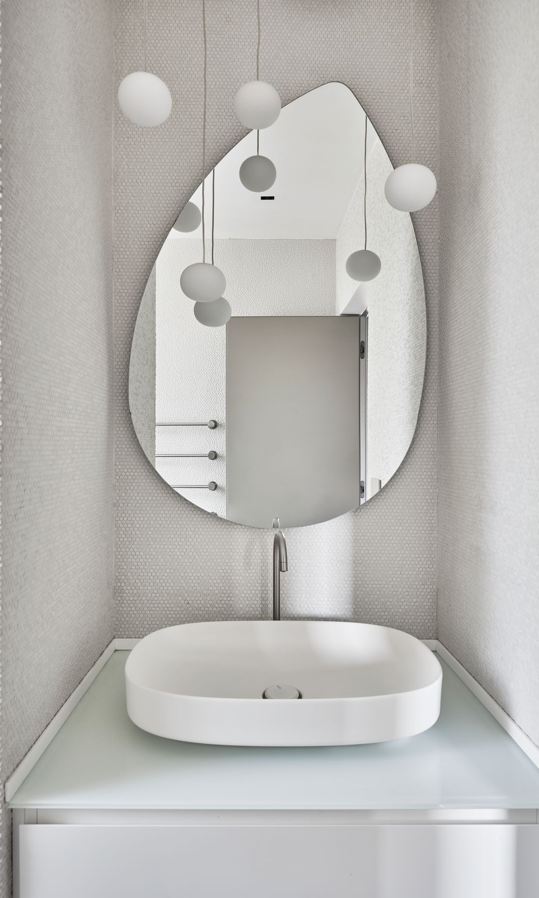 Aseo blanco con gotelé en paredes, lavabo blanco y espejo de formas orgánicas