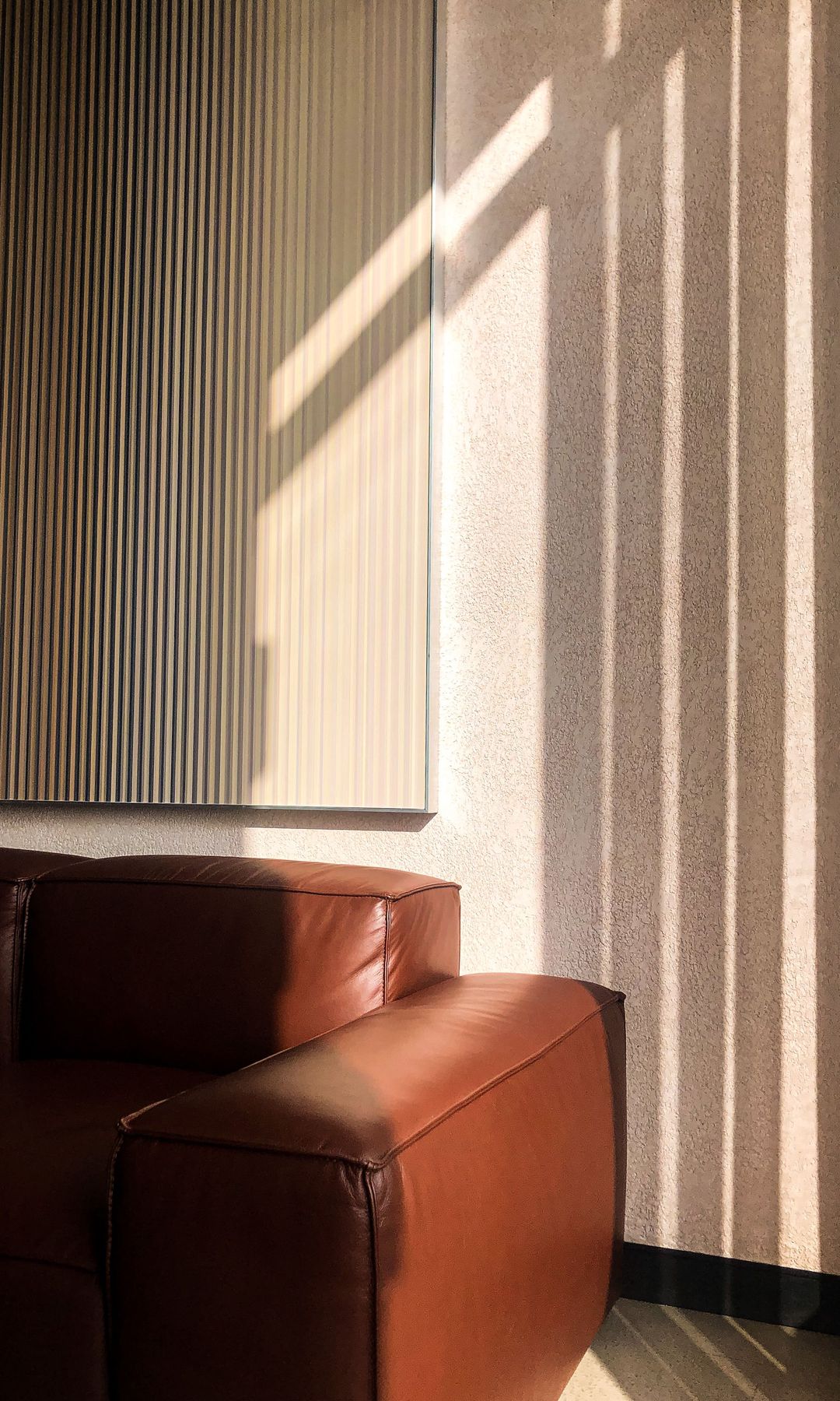 Pared del salón con gotelé, cuadro y sofá de cuero marrón 