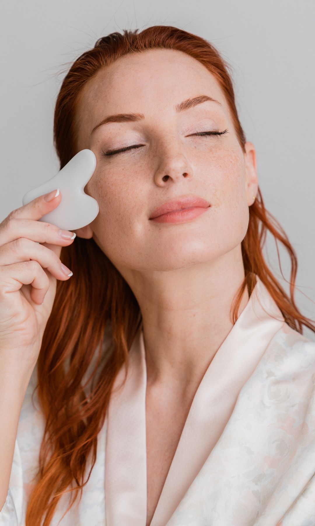 Rostro de mujer usando un masajeador facial piedra gua sha
