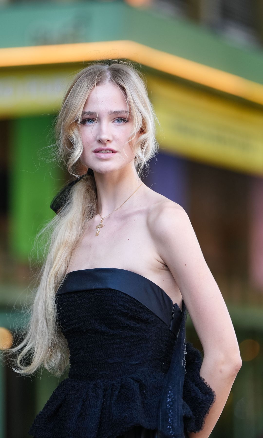 PARIS, FRANCE - JULY 09: A guest wears a strapless black dress featuring a textured, boucle-like fabric. The dress has a fitted bodice with a peplum detail at the waist and a voluminous A-line skirt. The hemline falls below the knee. Hair is styled in a long, loose braid, outside Viktor & Rolf, during Paris Fashion Week - Haute Couture Fall/Winter 2025/2026, on July 09, 2025 in Paris, France