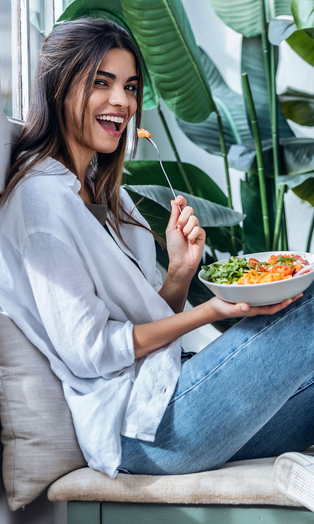 Mujer joven, sonriente, con un bol de ensalada