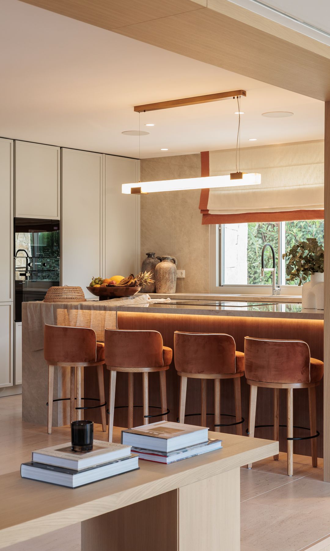 Cocina con isla con taburetes, lámpara de techo, muebles hasta el techo