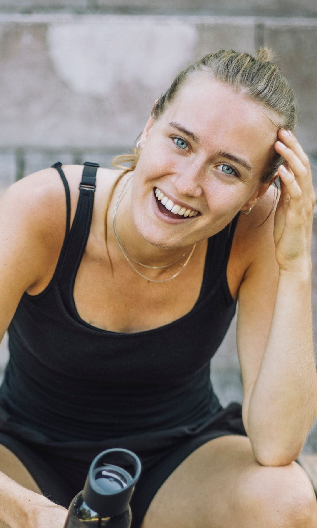 Mujer en ropa deportiva y sonriendo a cámara 