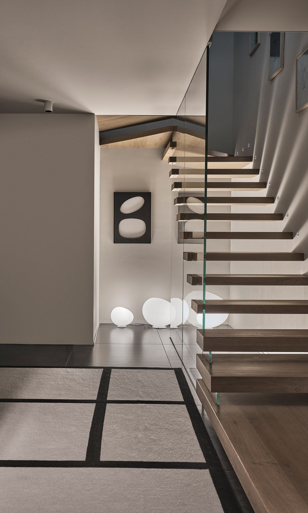 Escalera volada con los escalones de madera y barandilla de cristal 